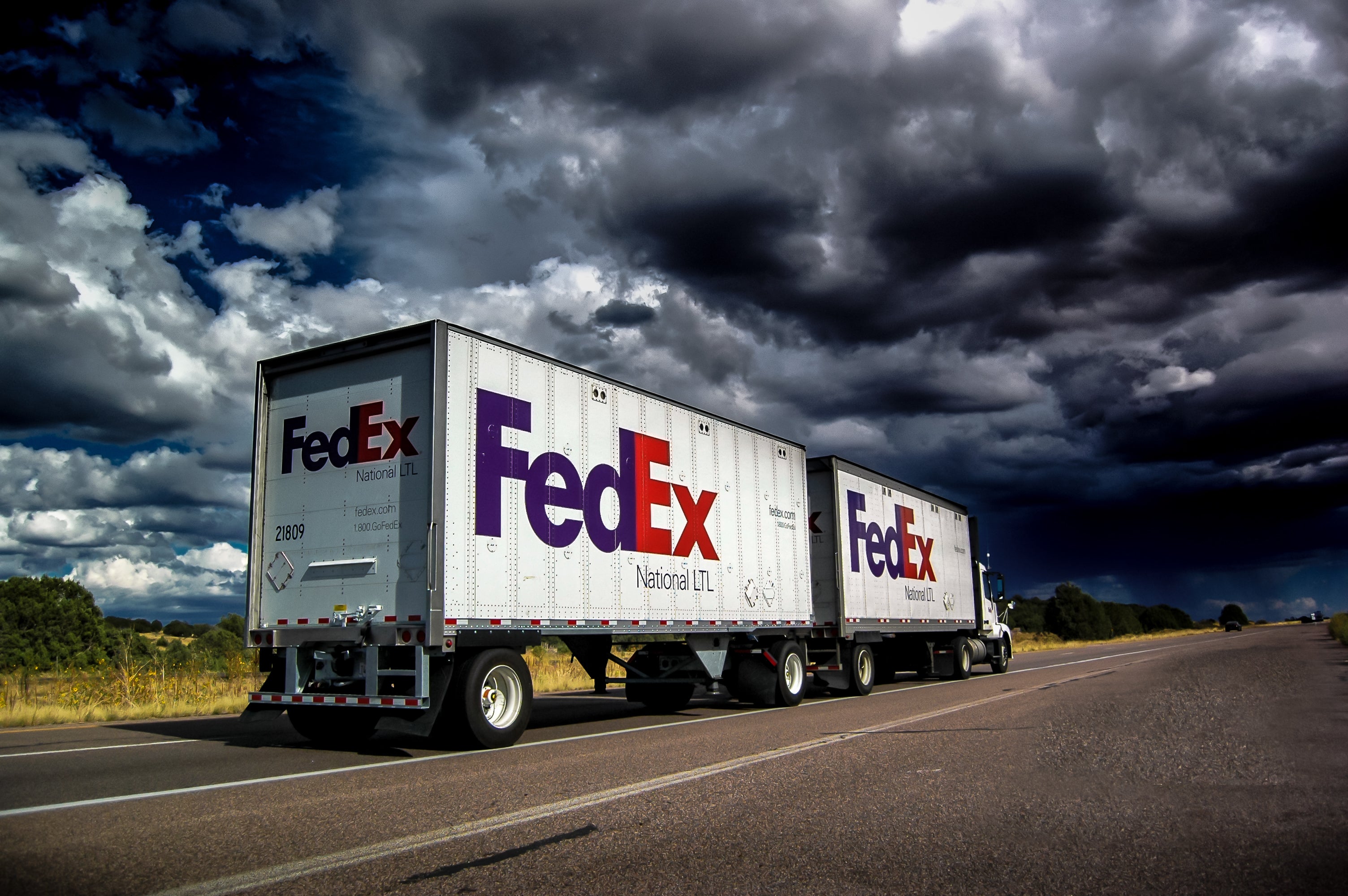 A white FedEx Freight truck pulling a double trailer. View from the rear side.