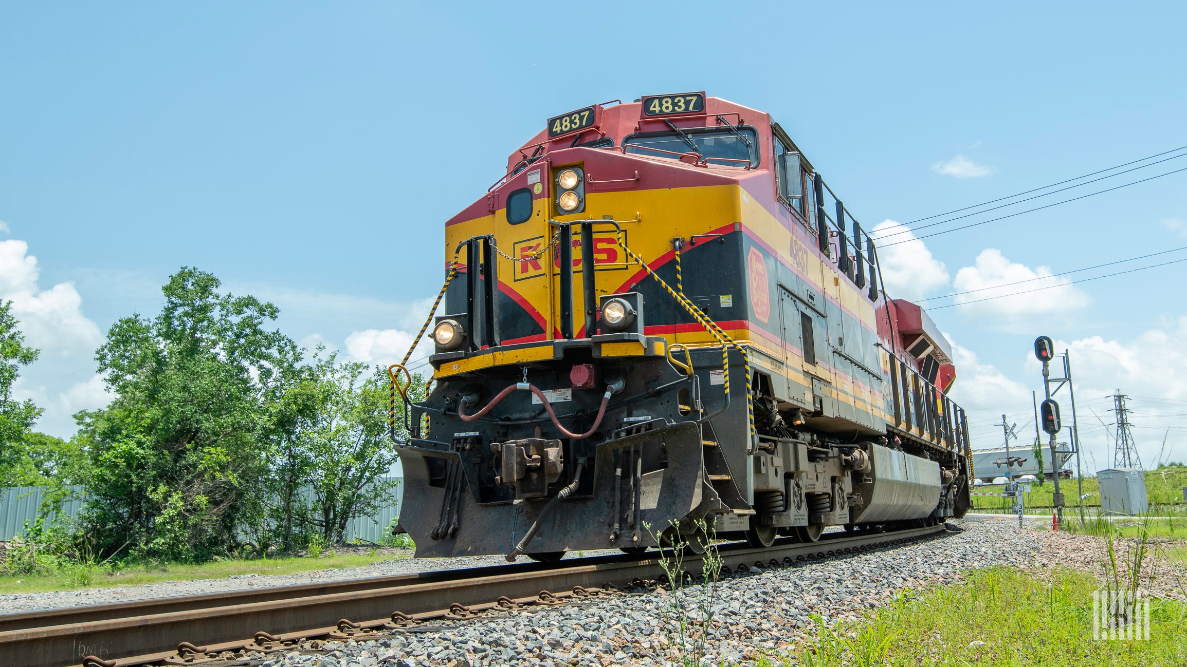 A photograph of a Kansas City Southern locomotive hauling intermodal containers.