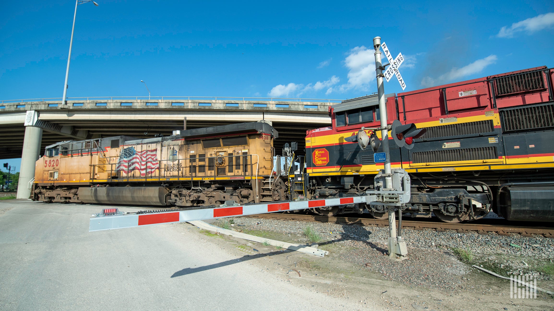 A photograph of a Union Pacific locomotive and a Kansas City Southern locomotive at a rail crossing.