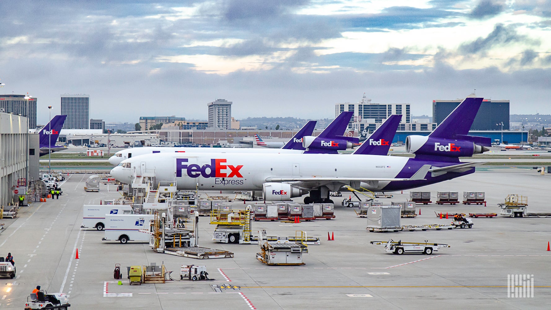 Several FedEx planes lined up at an airport terminal.