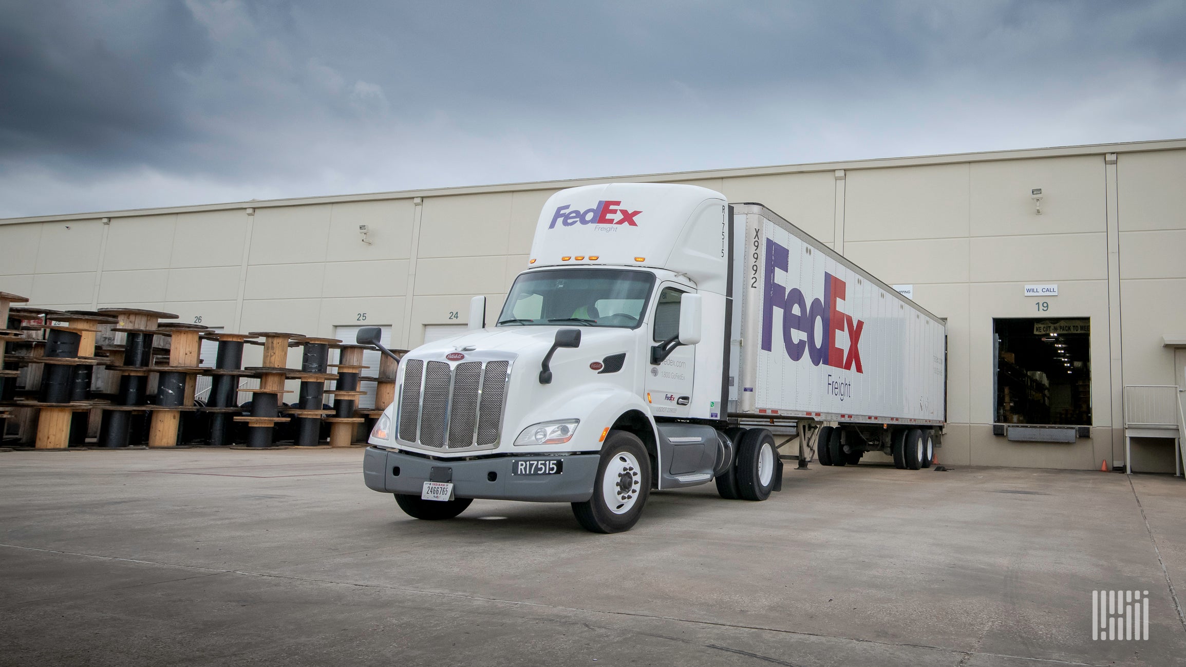 A white FedEx tractor trailer at a warehouse door.