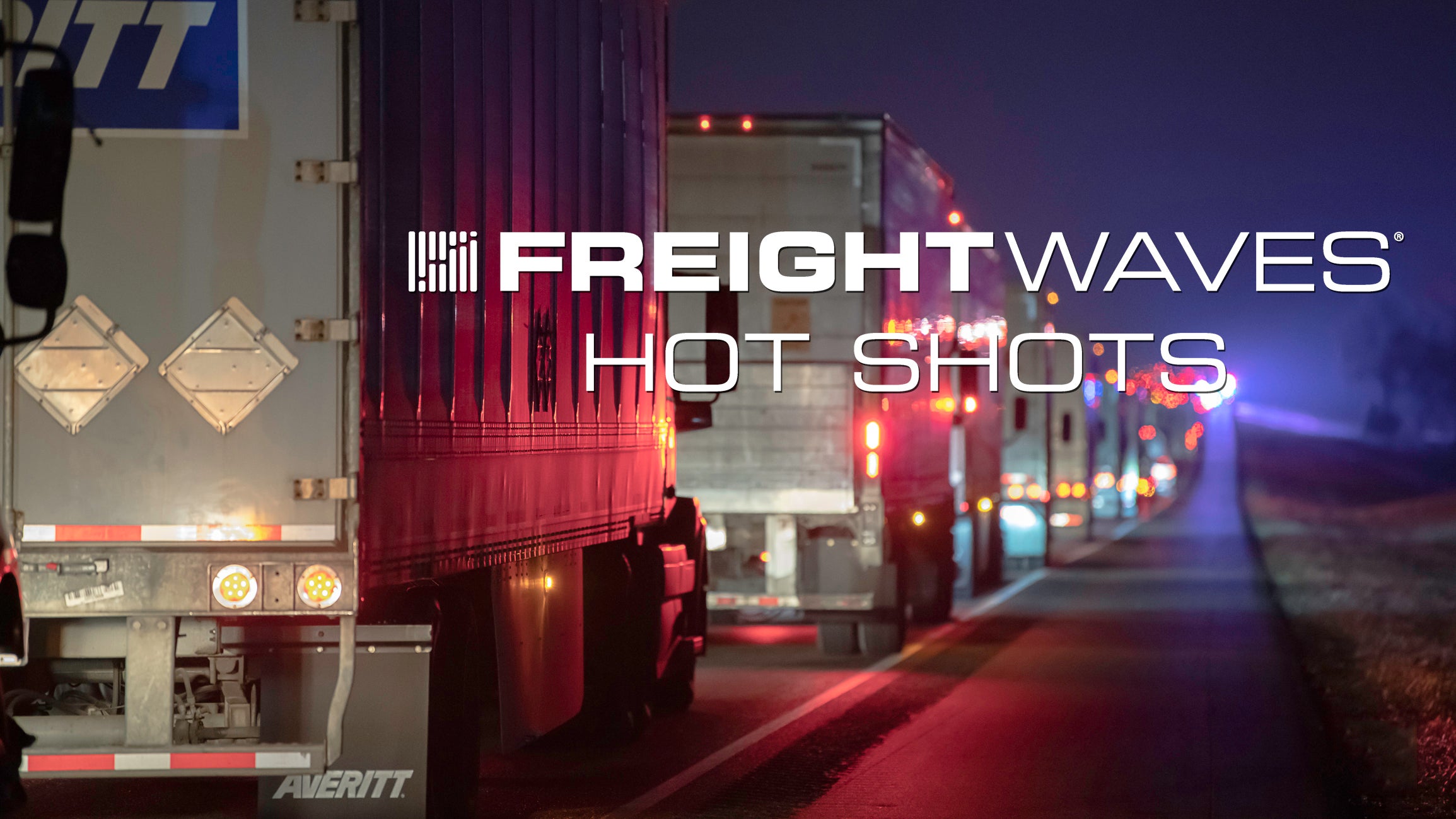 Line of tractor-trailers on a highway at night with "FreightWaves Hot Shots" logo.