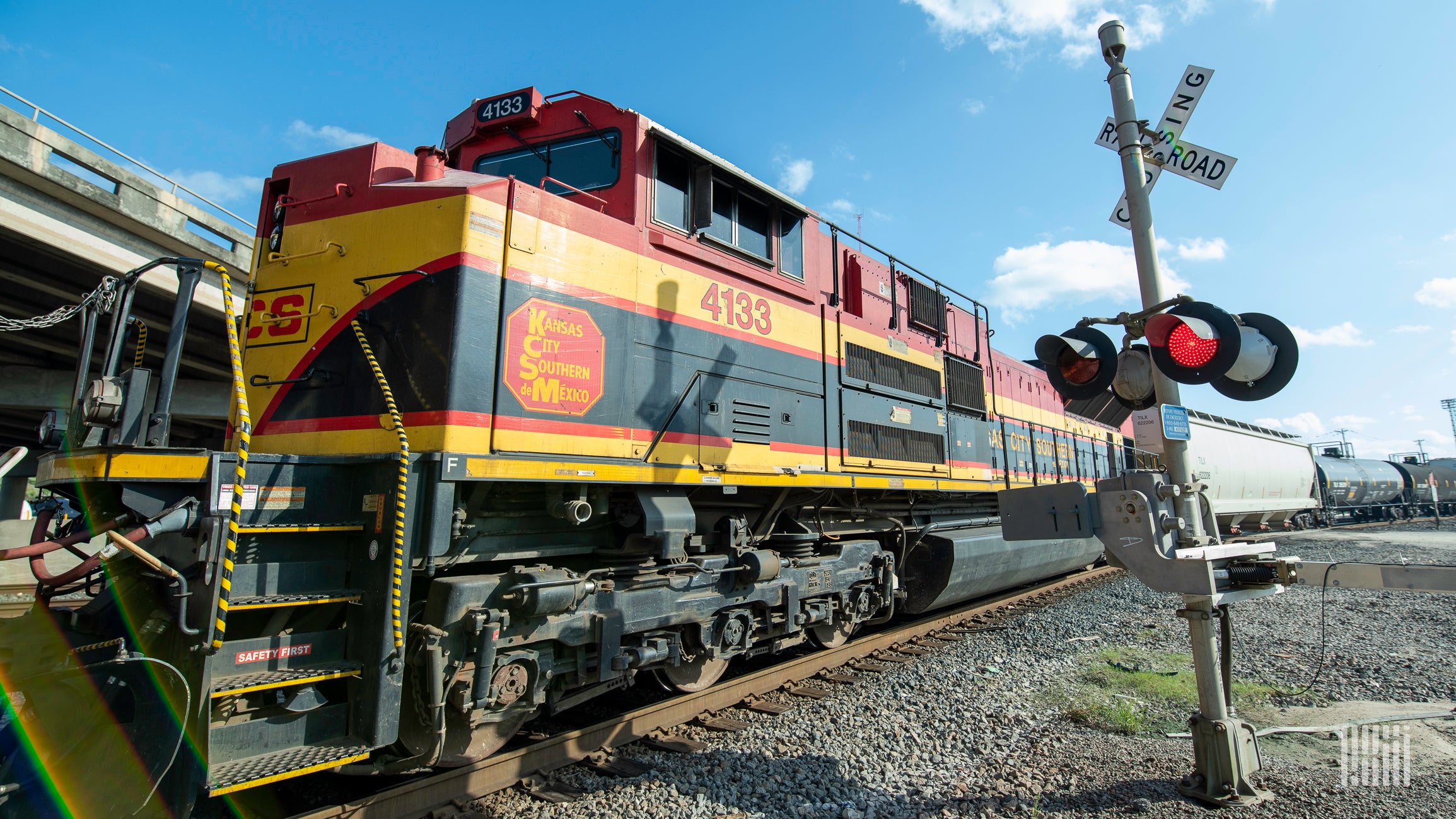 A photograph of a Kansas City Southern train at a rail crossing.