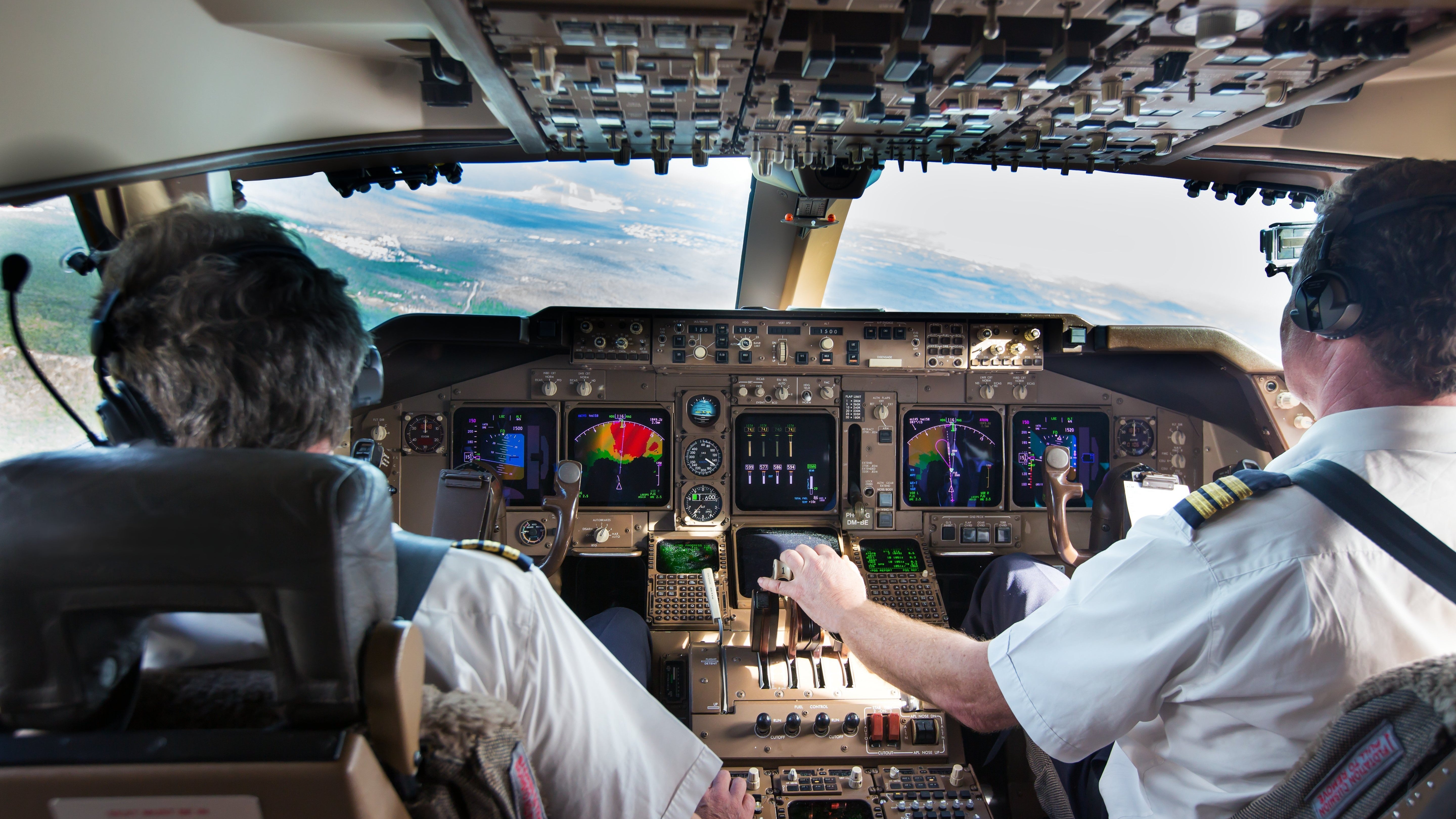 Pilots in cockpit. View from behind looking out the window during flight.