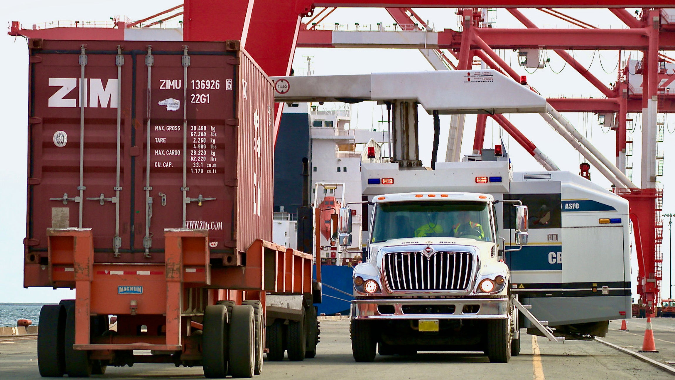 Canada Border Services Agency officers prepare to inspect a red intermodal container.