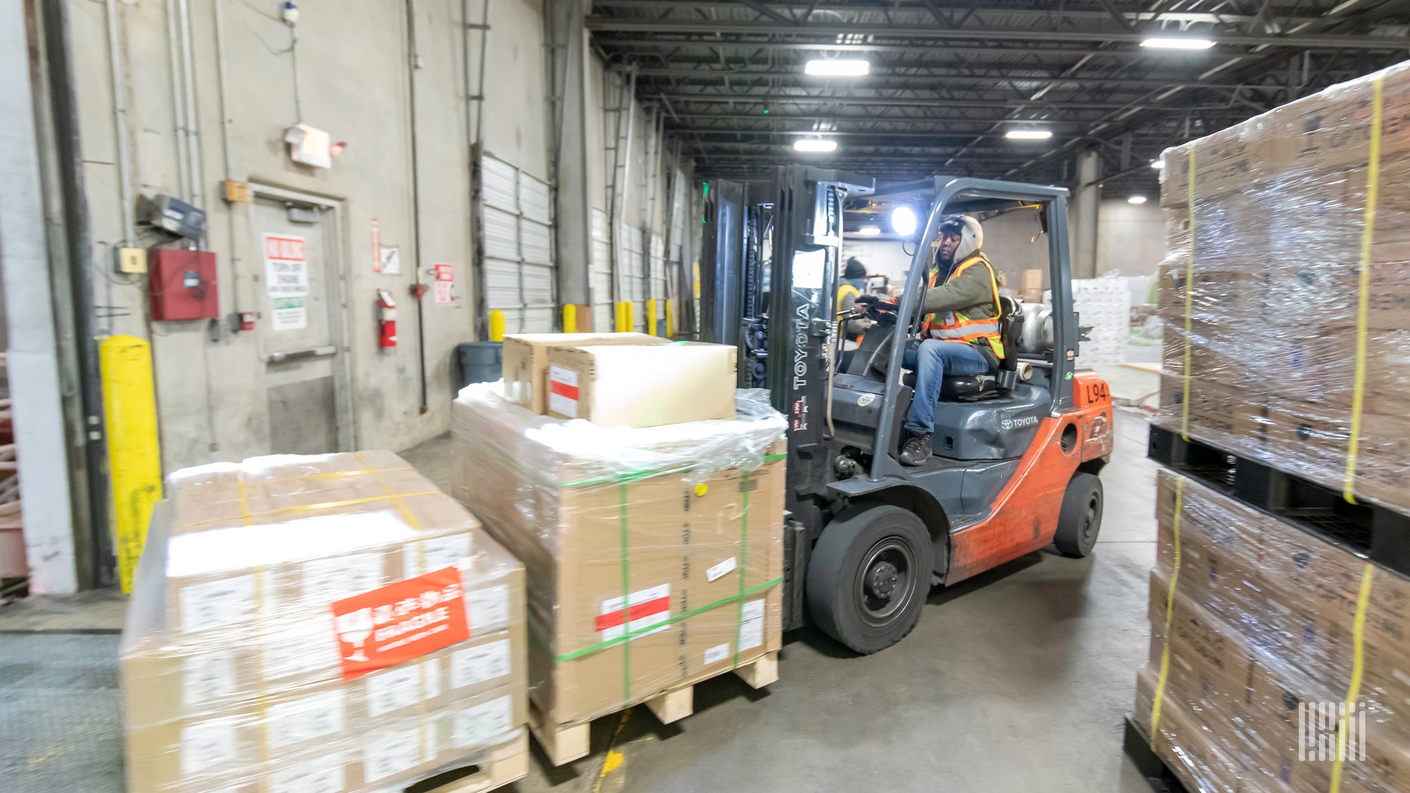 A forklift moves wooden pallets of goods at an airfreight warehouse.