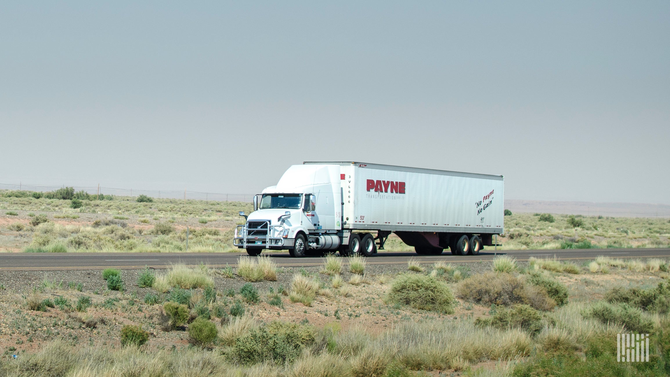 A tractor-trailer of Mullen Group trucking company Payne viewed from the side of a road.