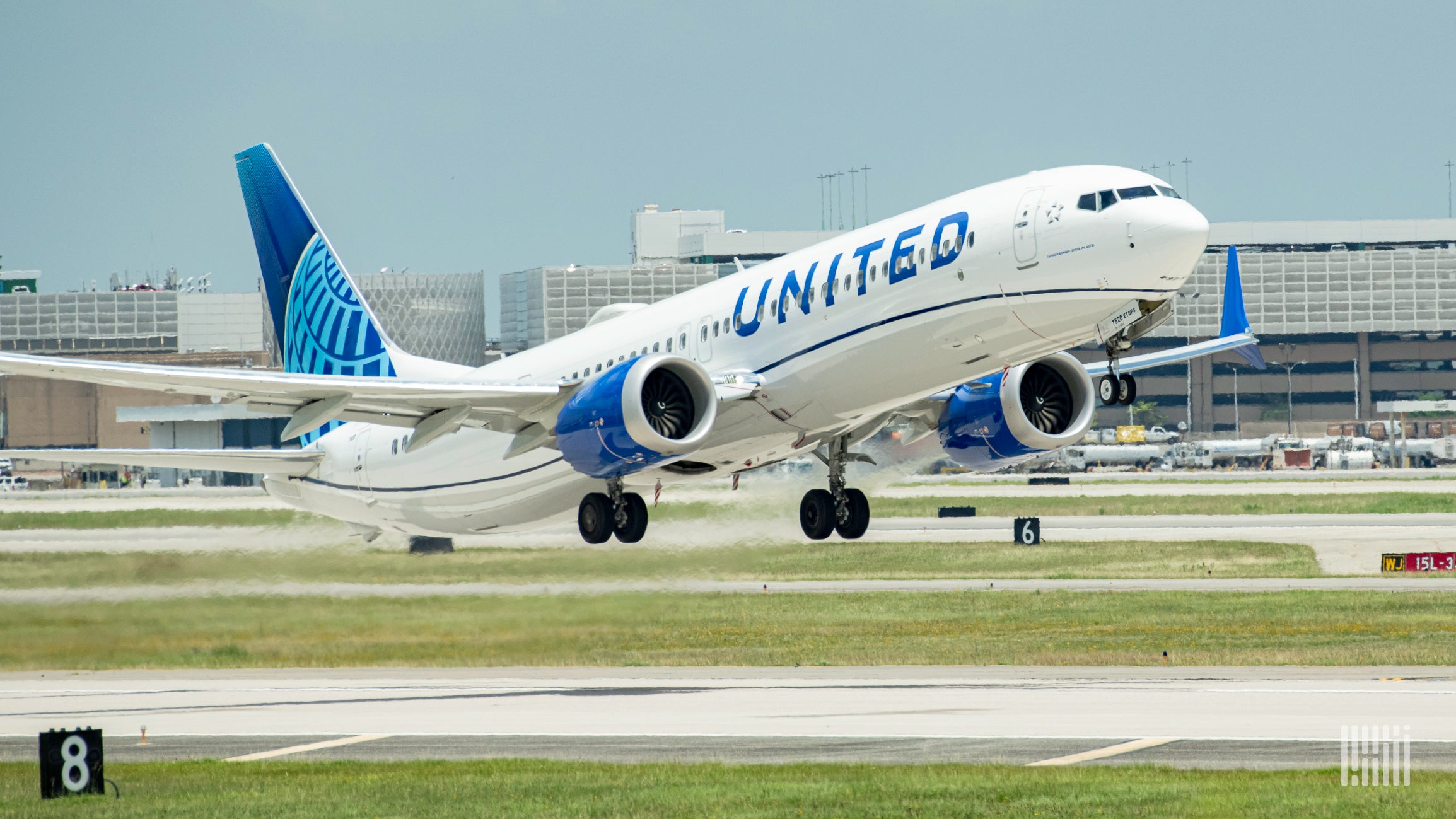 A white United Airlines jet with blue tail touches down on the runway.