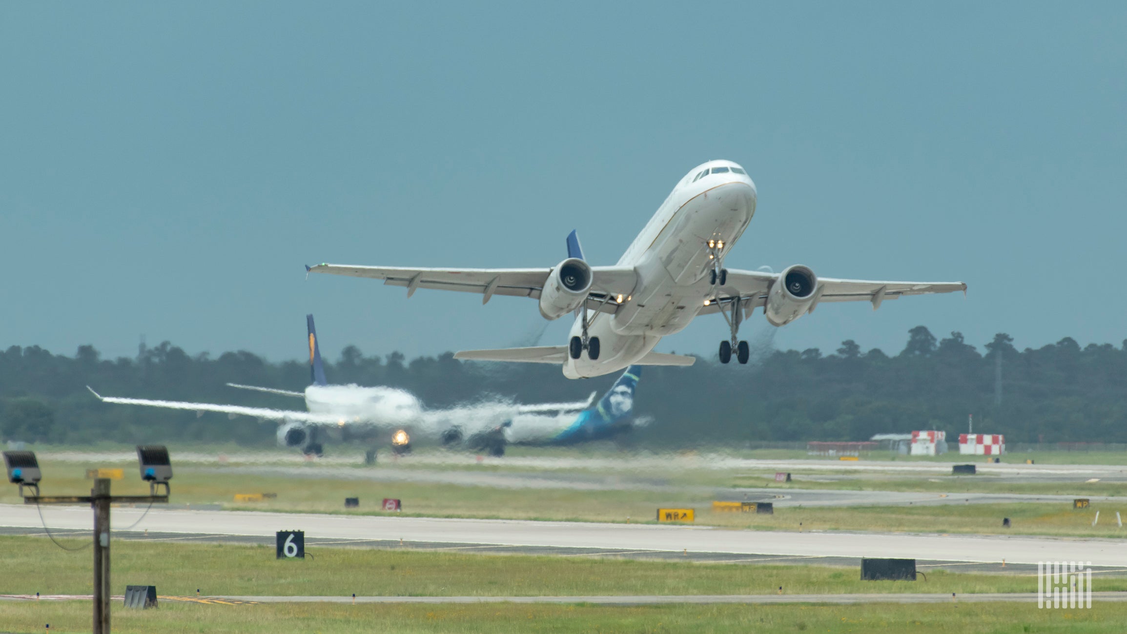 A white plane takes off with view facing the aircraft.