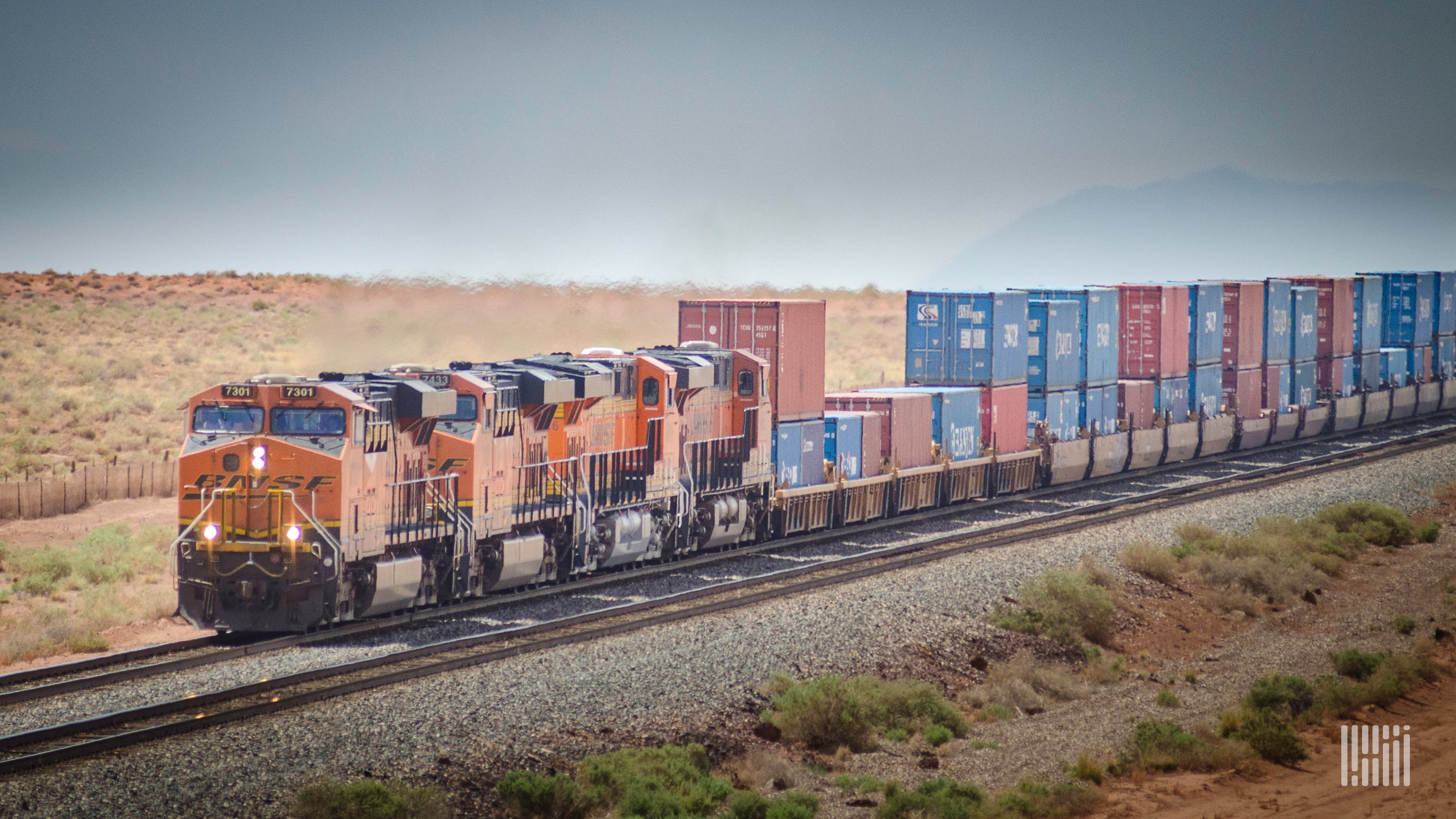 A photograph of a BNSF train hailing intermodal containers across a desert.