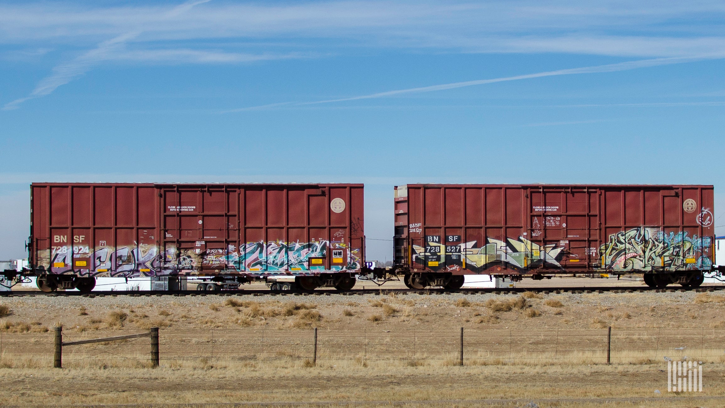 A photograph of two boxars rolling down train track.