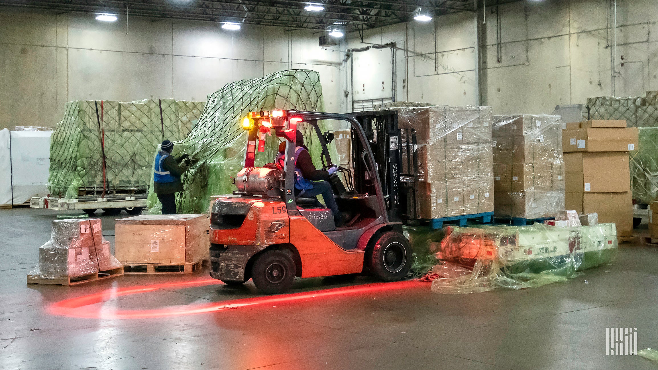 A forklift moving stacks of boxes in a warehouse.