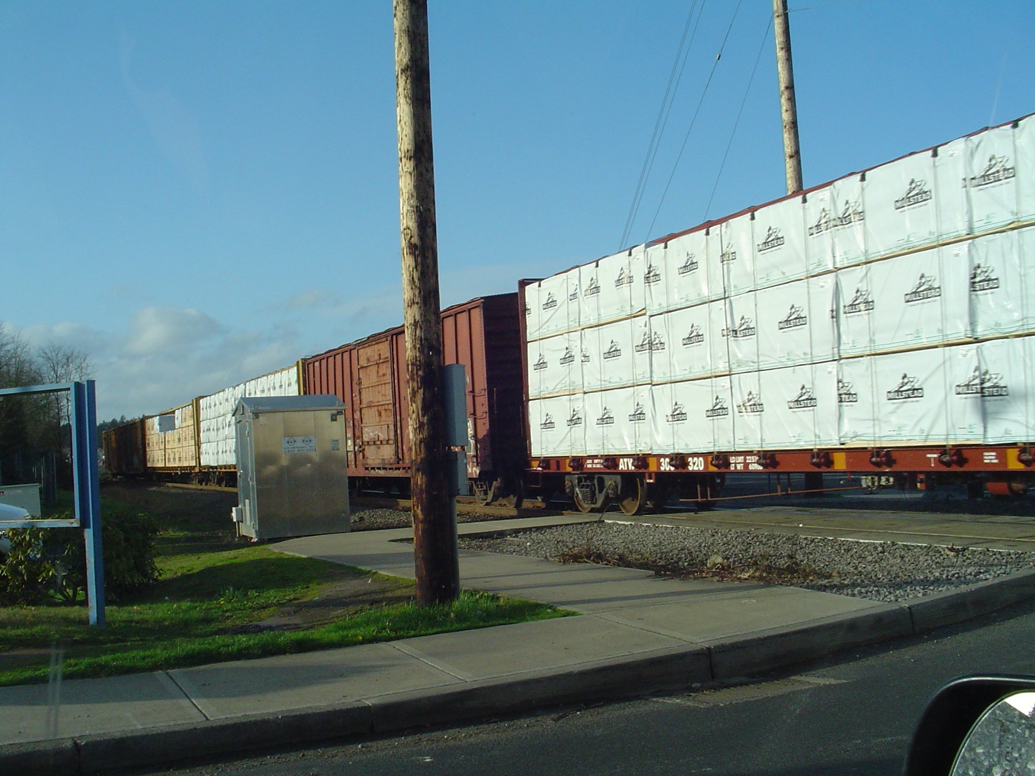 A photograph of a train rolling past a rail crossing.