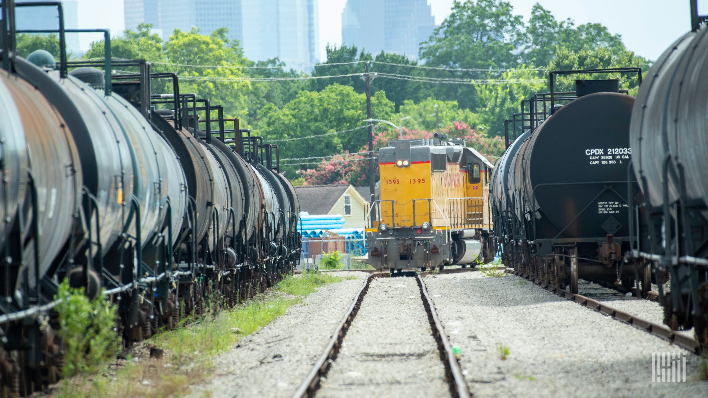 A photograph of a Union Pacific locomotive driving past parked train cars in a rail yard.