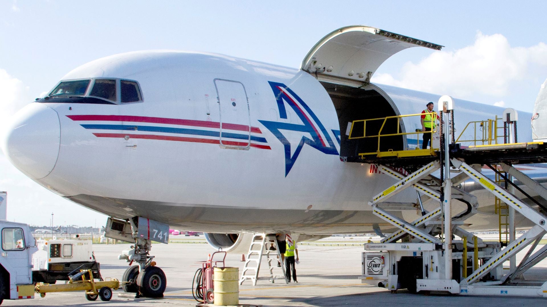 A white jet with cargo door wide open on a bright sunny day.