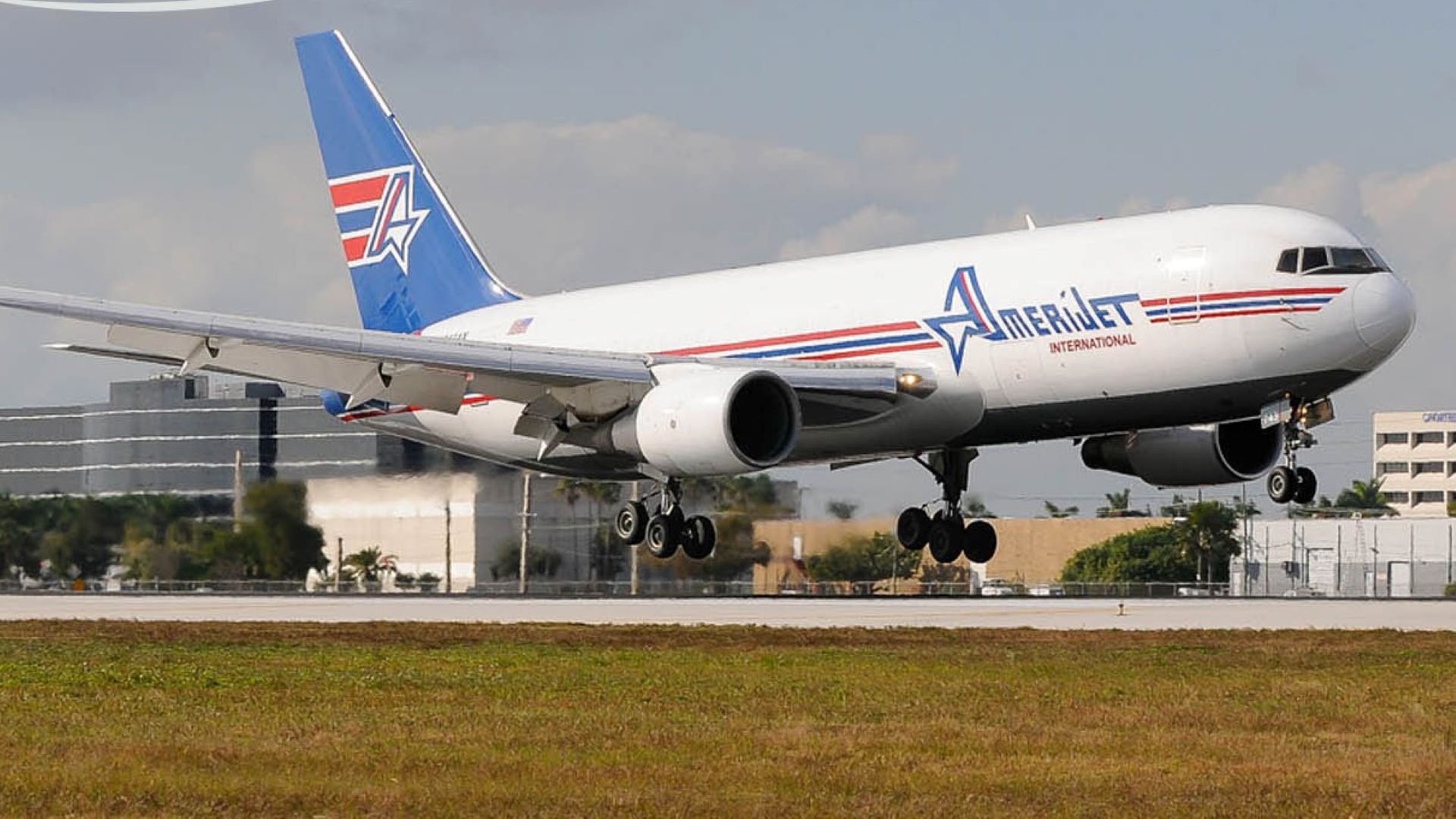 A white Amerijet cargo plane with a blue tail landing on runway.