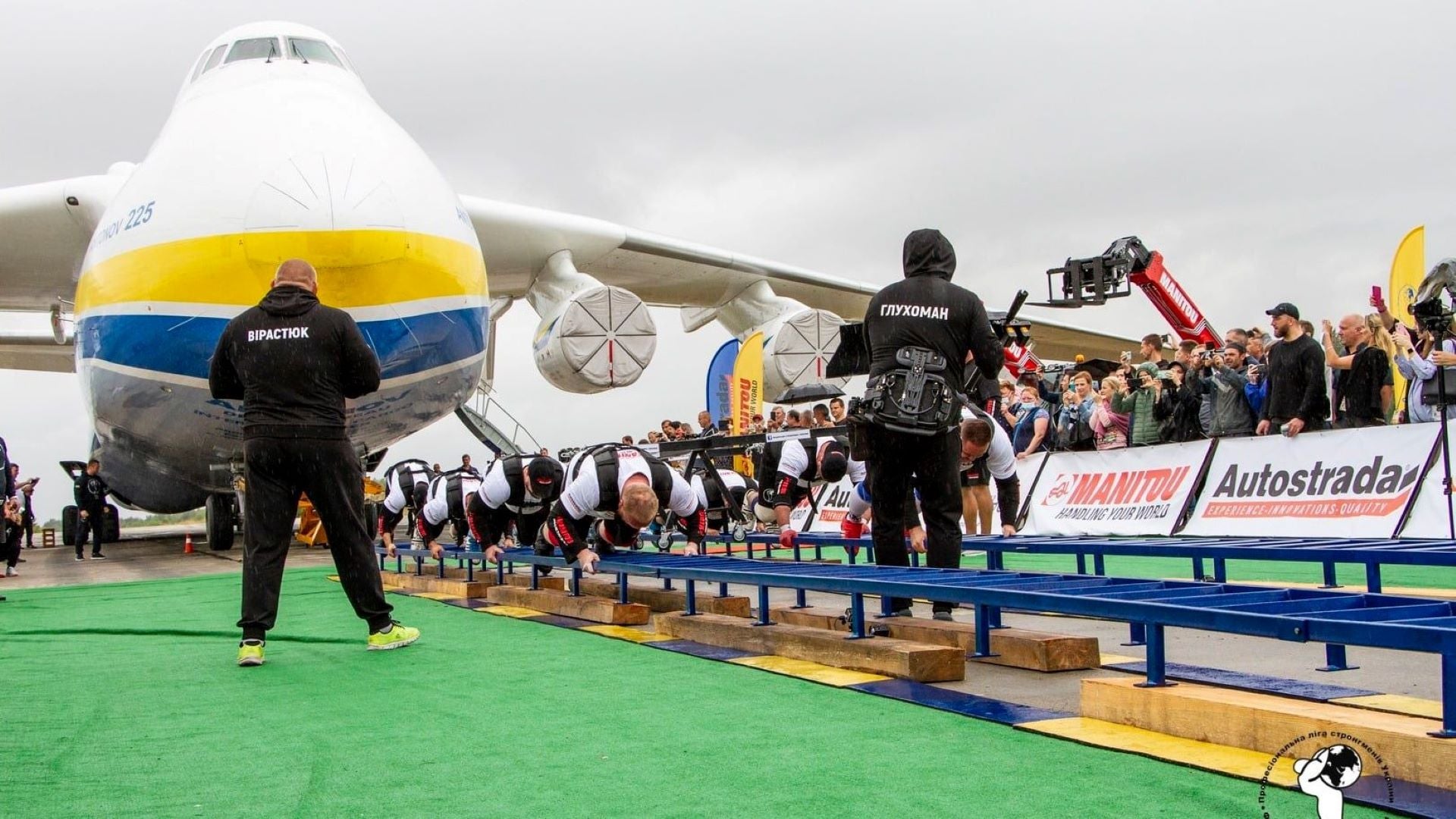 A group of men crawling to pull a massive plane with crowed cheering on.