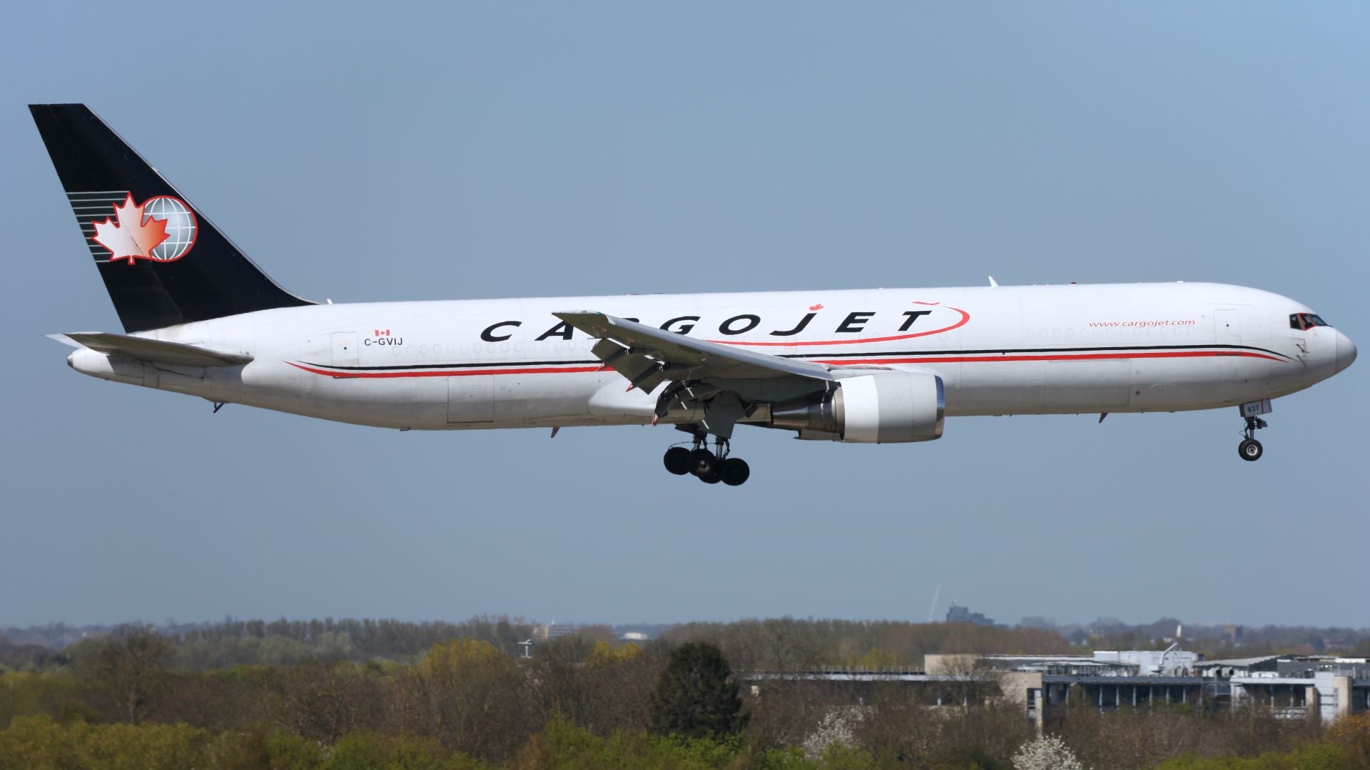 A Cargojet jet, white with blue tail, comes in for a landing with wheels extended.