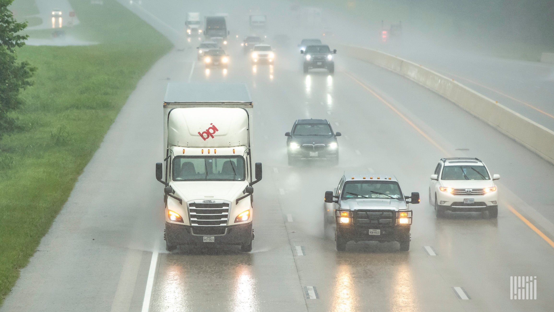 Trucks and cars on a highway during heavy rain.