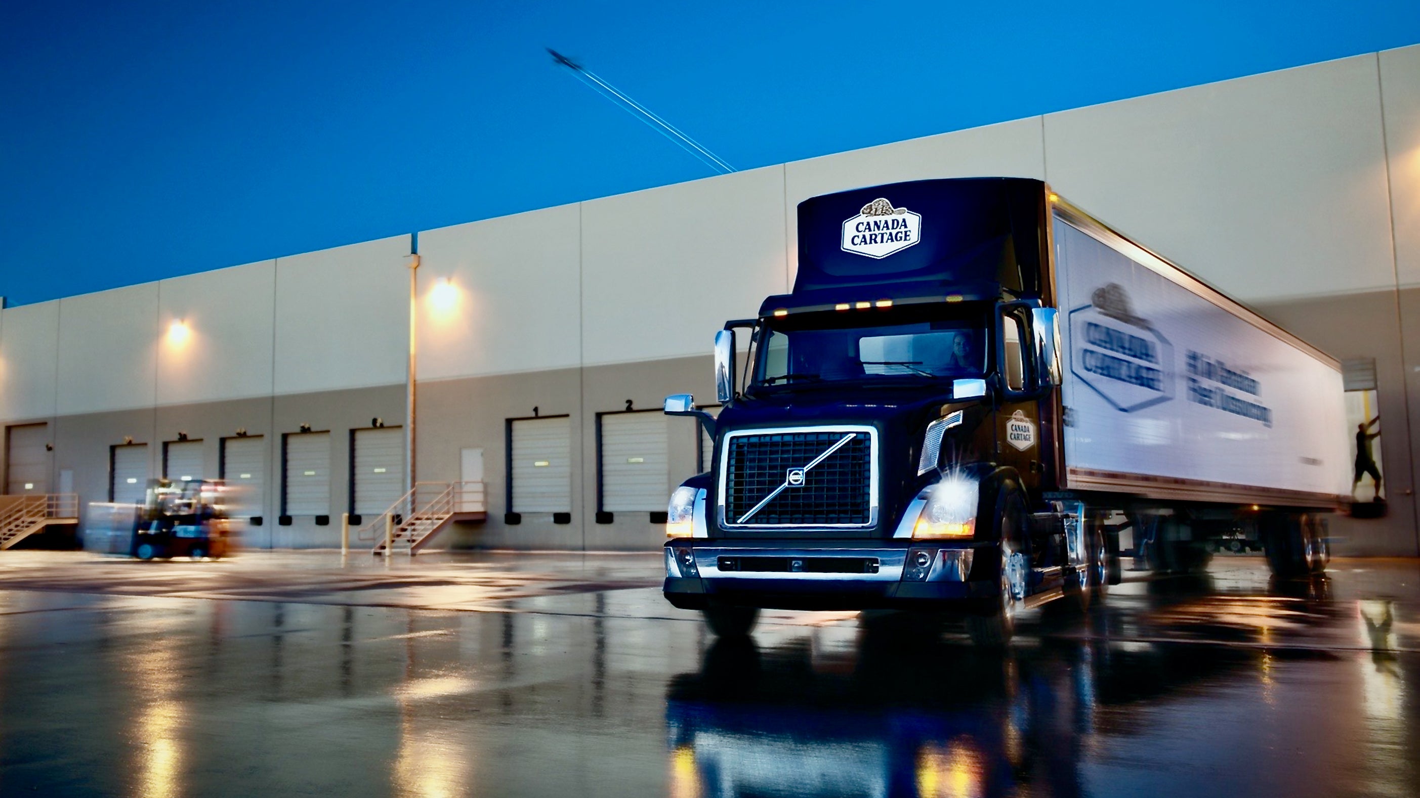 A truck from Canada Cartage exits a loading dock.