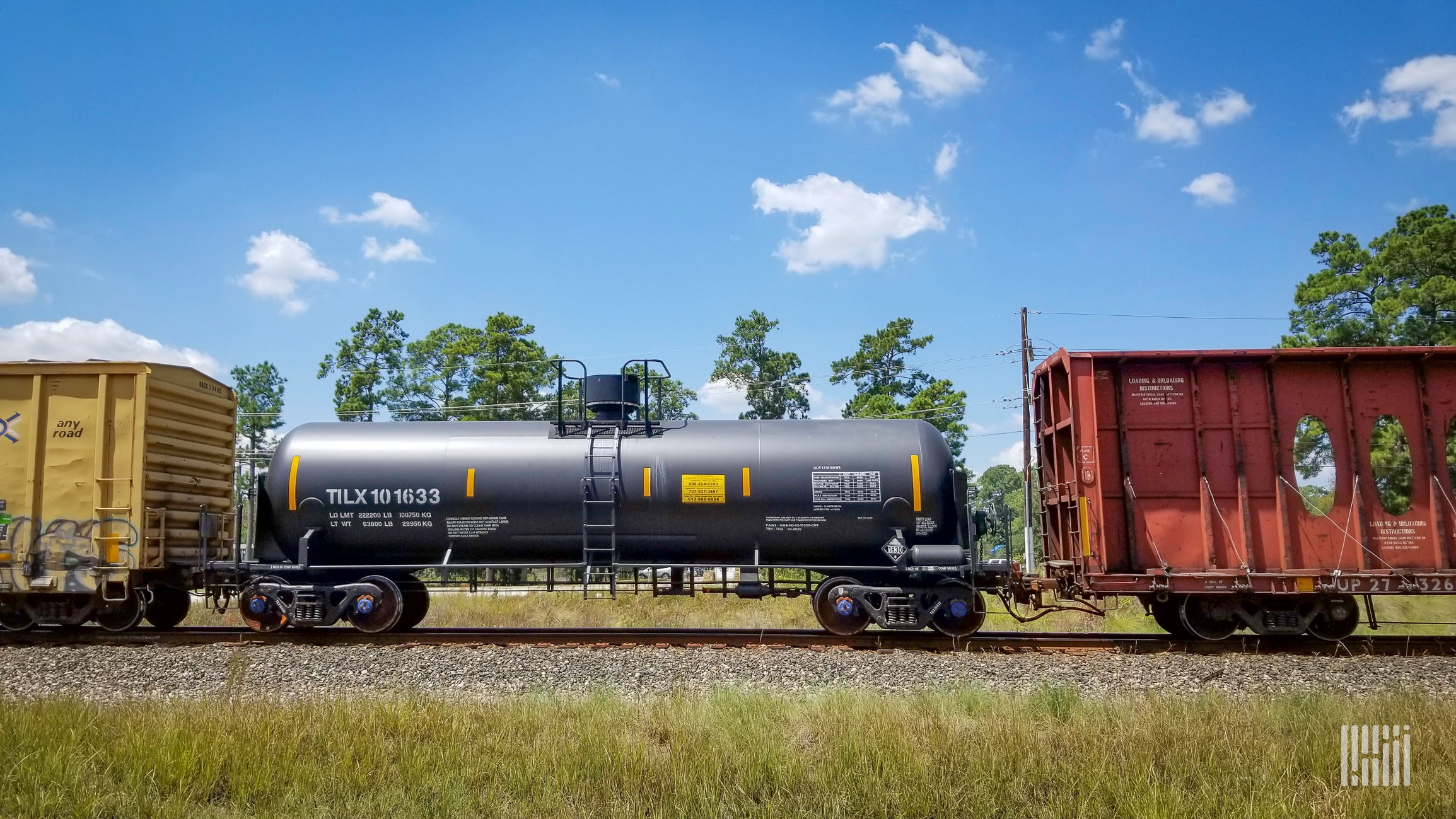 A photograph of a two boxcara and a tank car on train tracks.