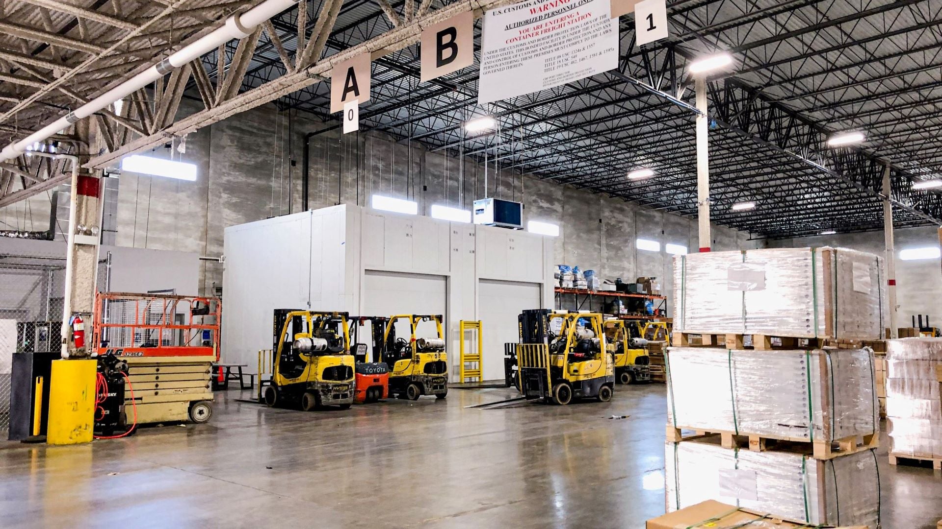 Inside an airfreight warehouse, with forklifts parked.