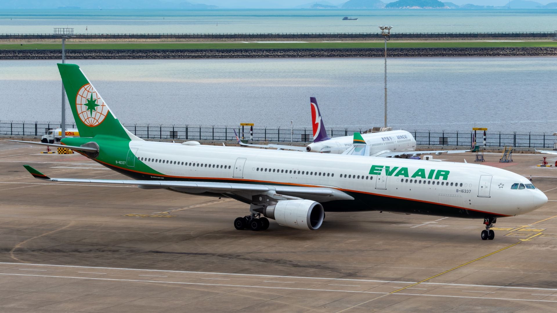 An EVA Air A330 on the tarmac with a bod of water in the background.