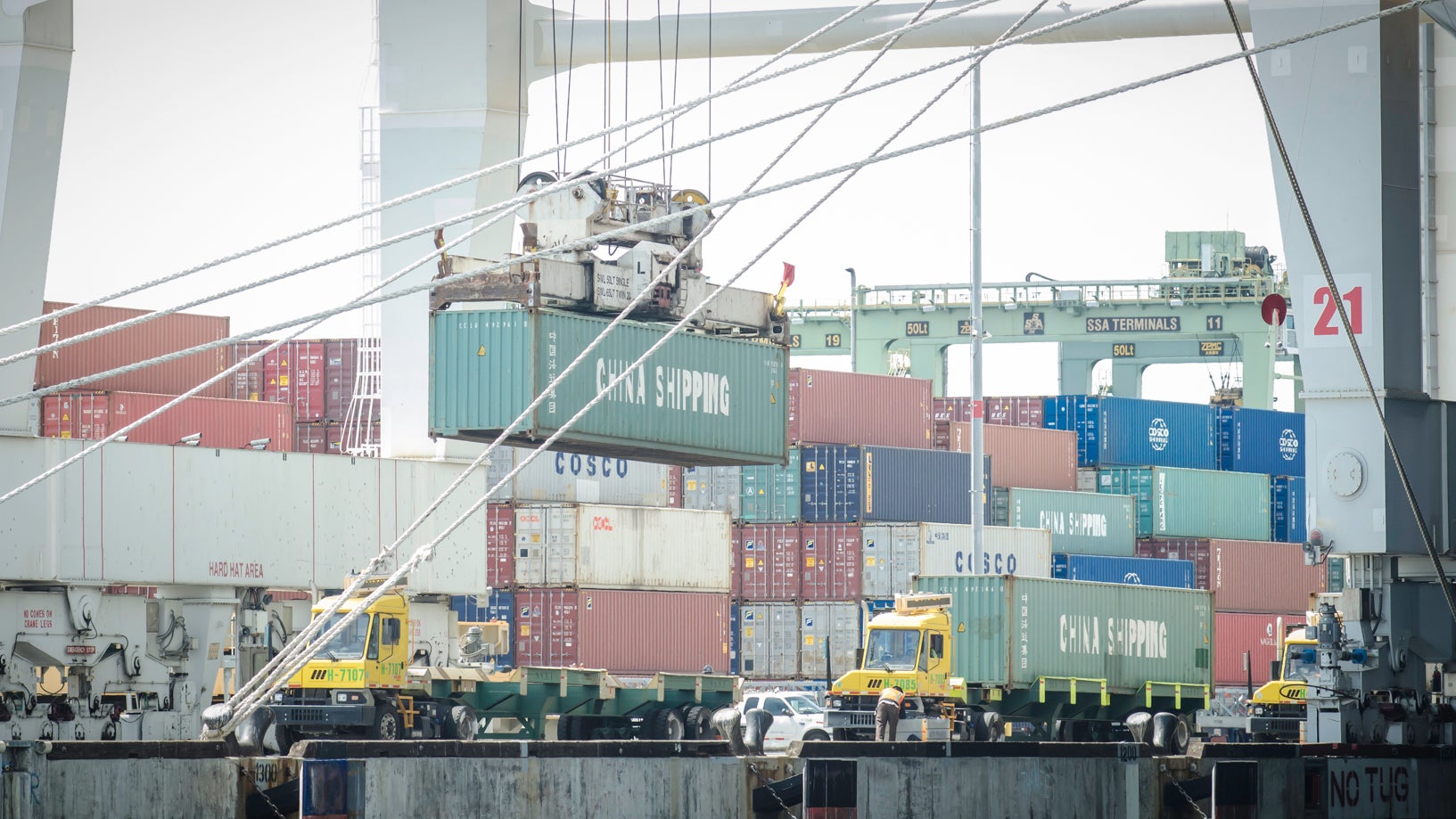 Cranes lifting containers off a vessel onto shuttle tractors.