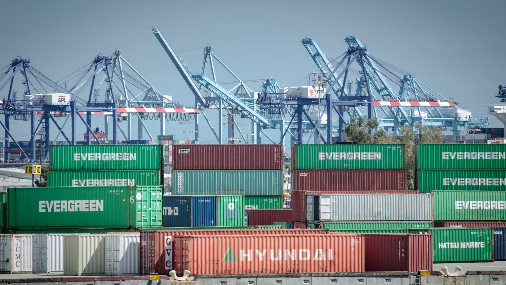 Containers and cranes in the background at a big port.