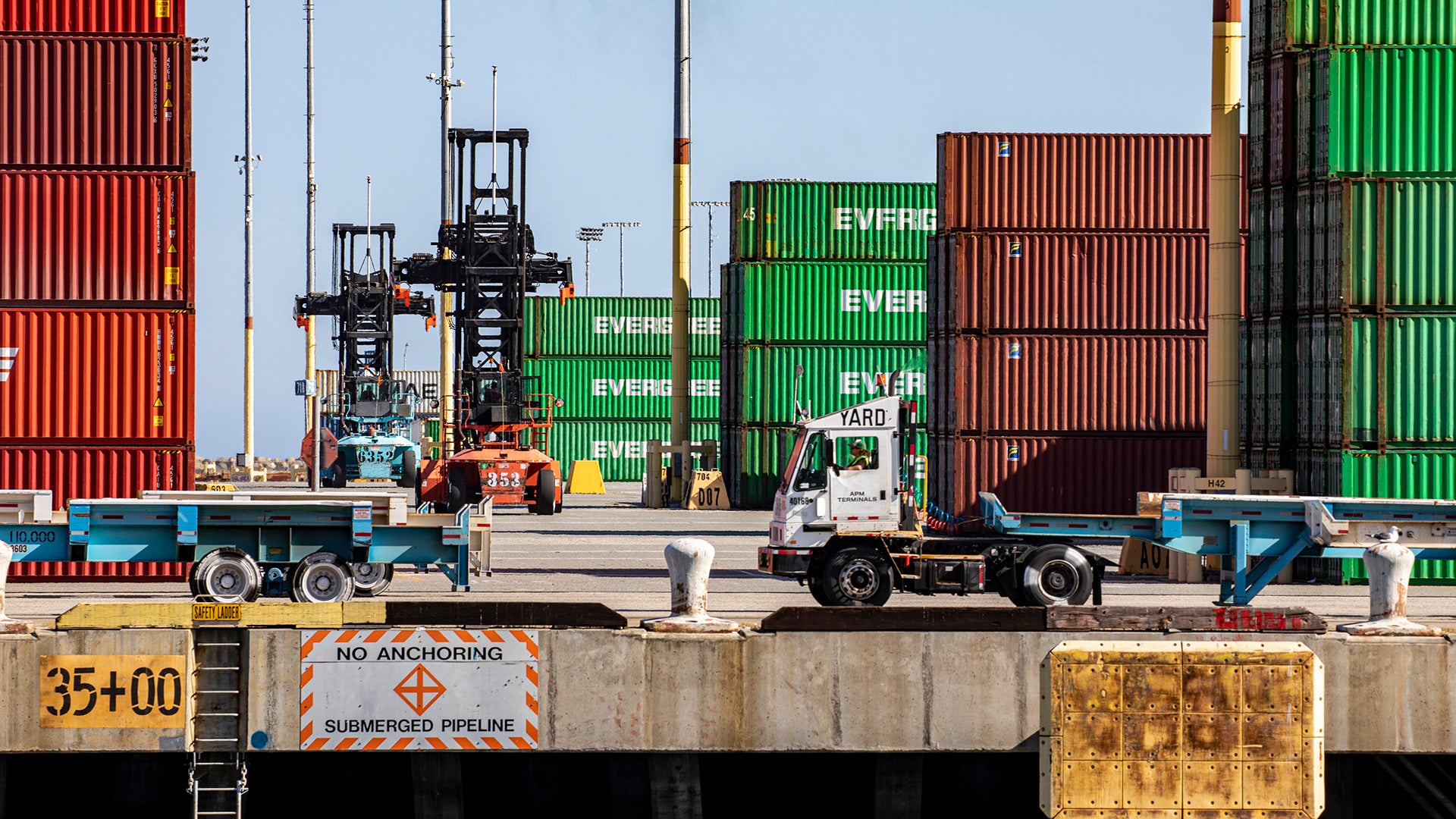 Tractors and containers moving about a marine terminal at a port.