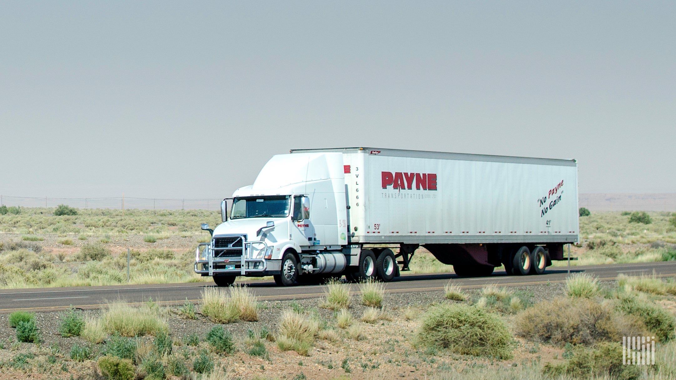 A tractor-trailer from Mullen Group trucking company Payne Transportation travels on a highway, viewed from the side of the road.