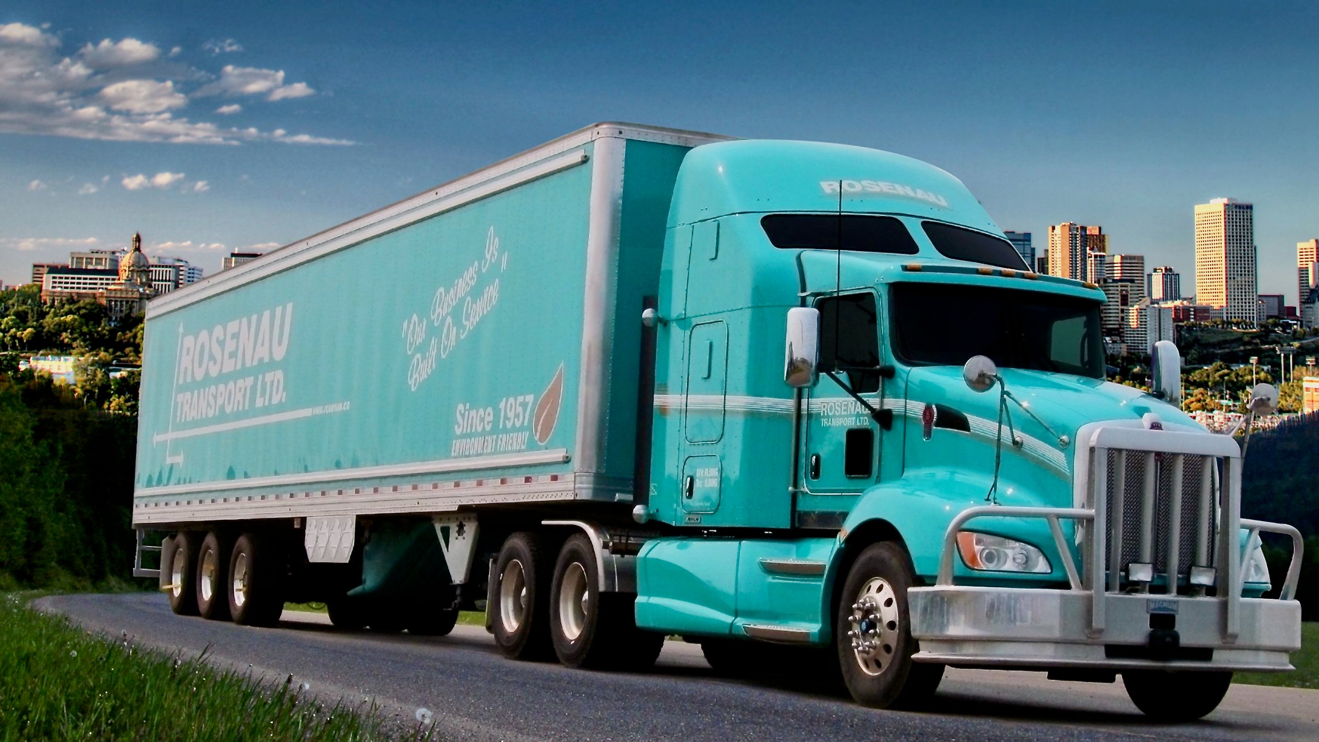 A tractor-trailer of Rosenau Transport against a city background.