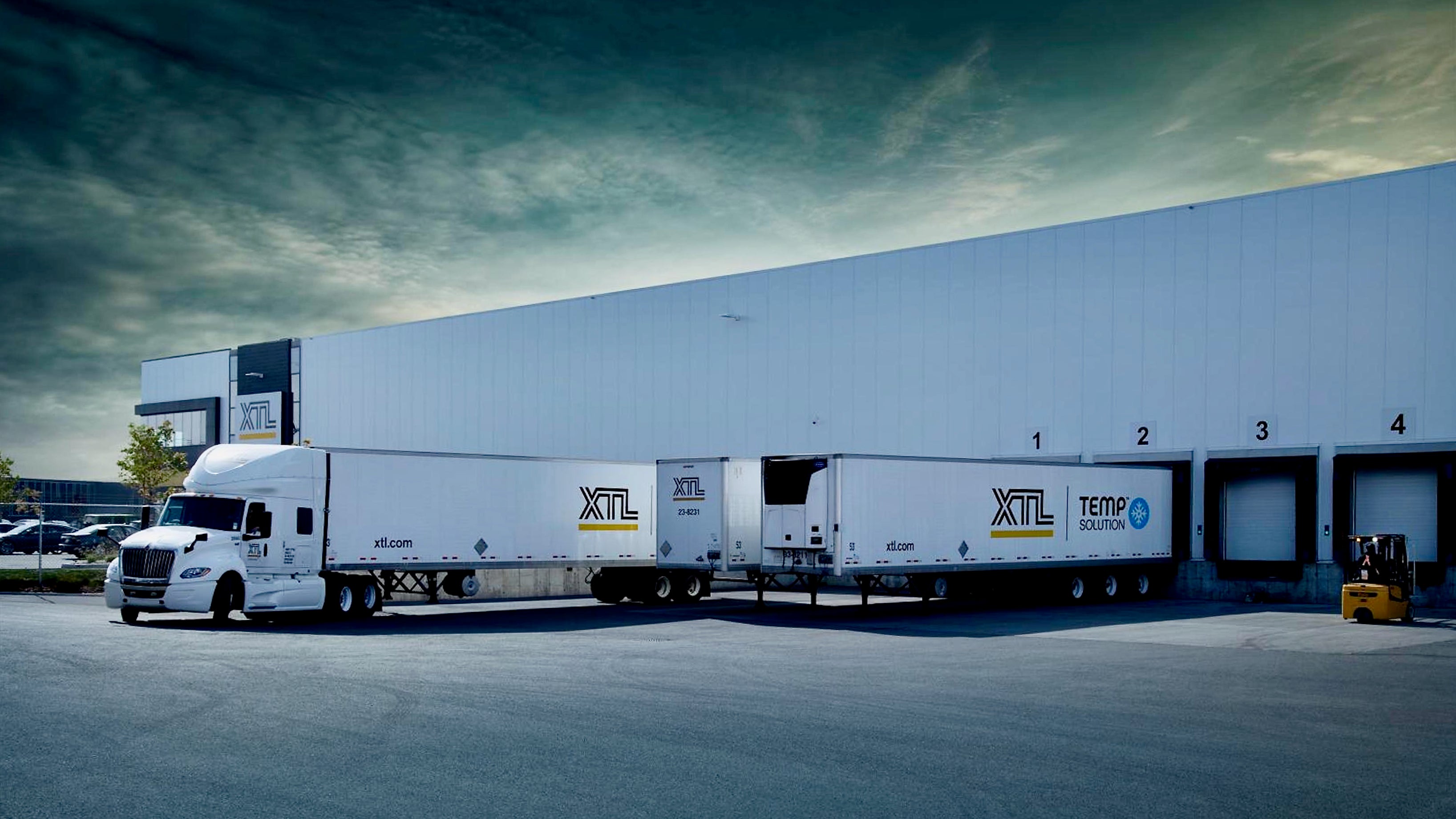 Tractor-trailers of XTL at a company load facility.