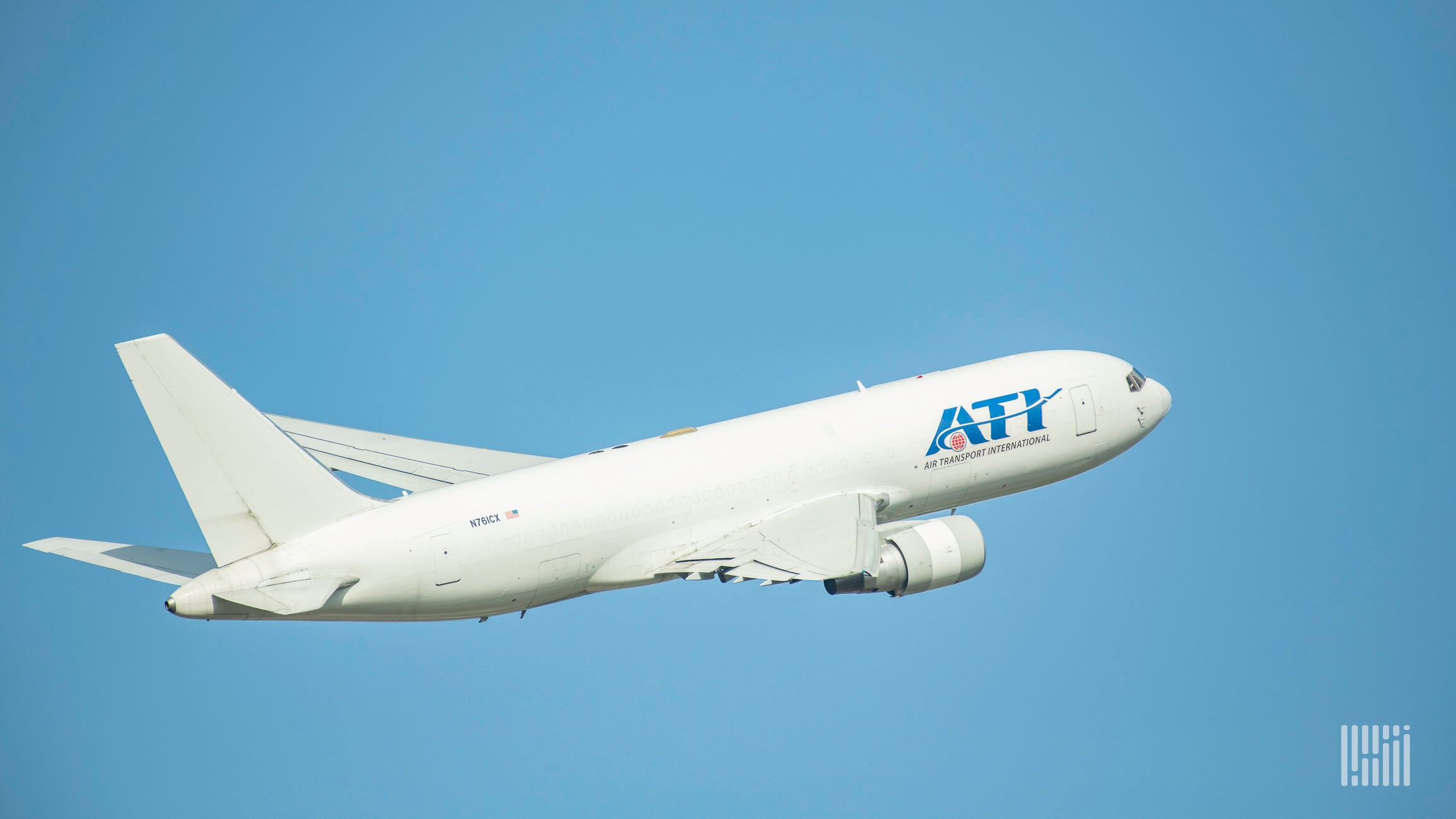 A white jet with the ATI logo flies high into a blue sky.