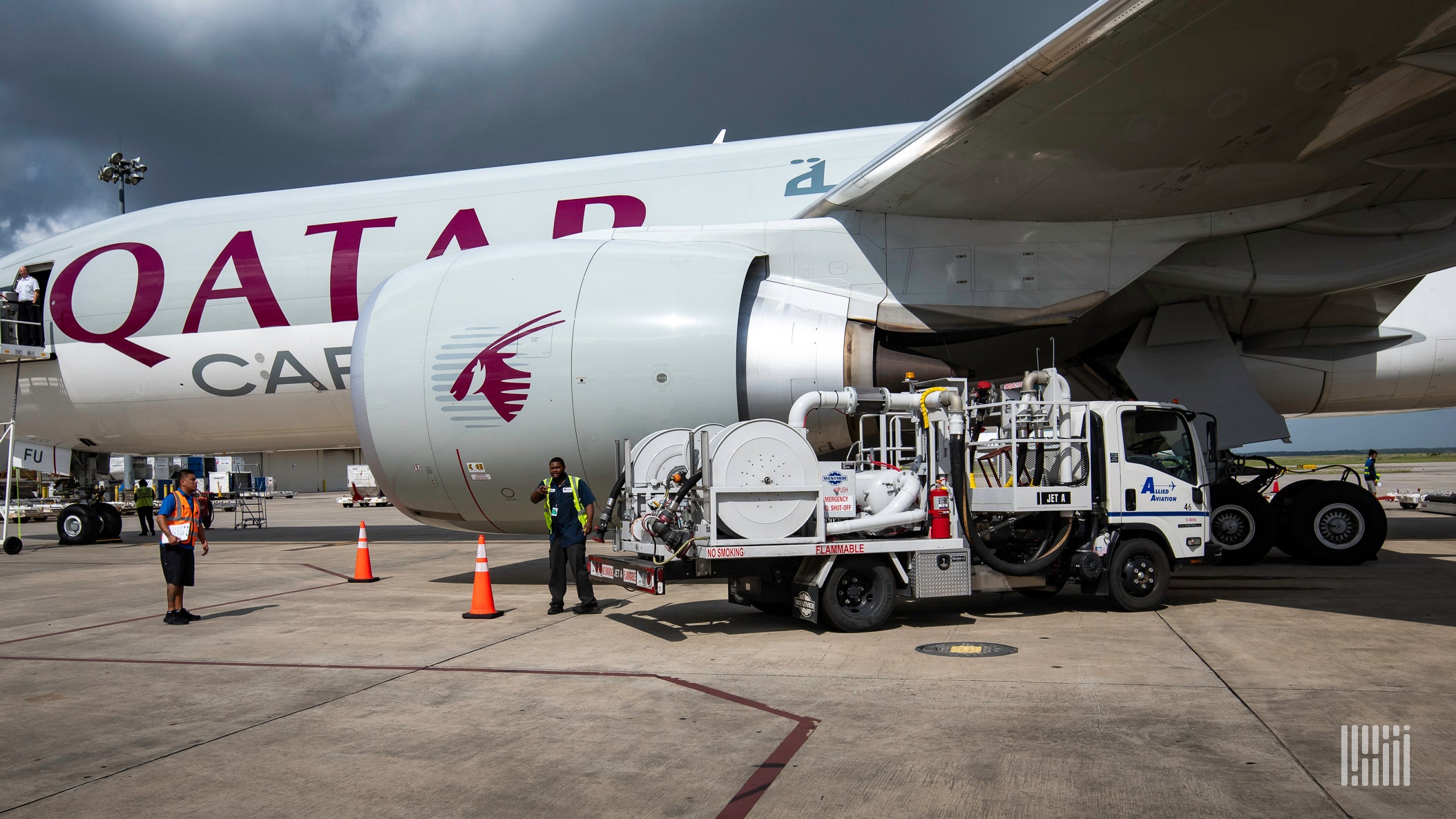 A Qatar Airways cargo plane being refueled by a tanker truck.