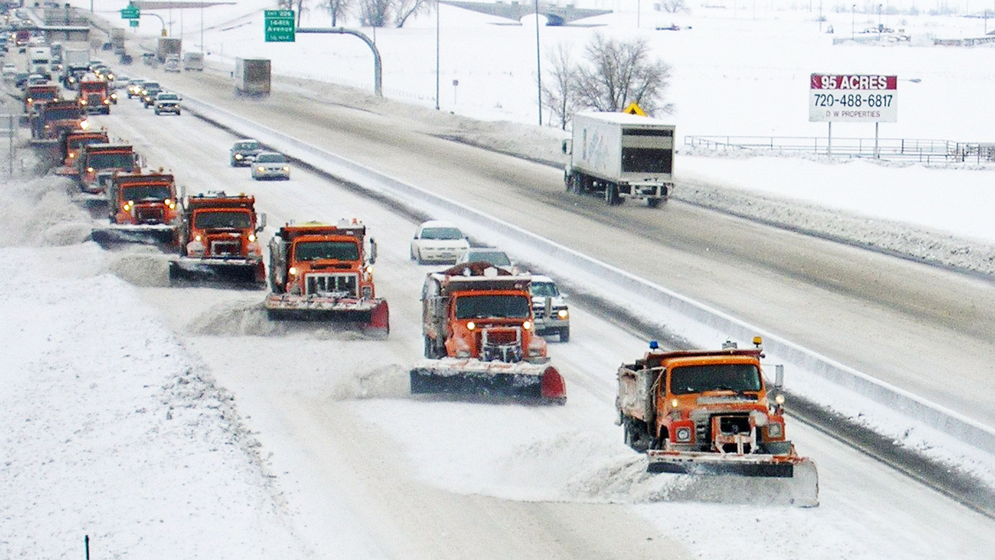 Cars, tractor-trailers and plow trucks on a snowy Colorado road.