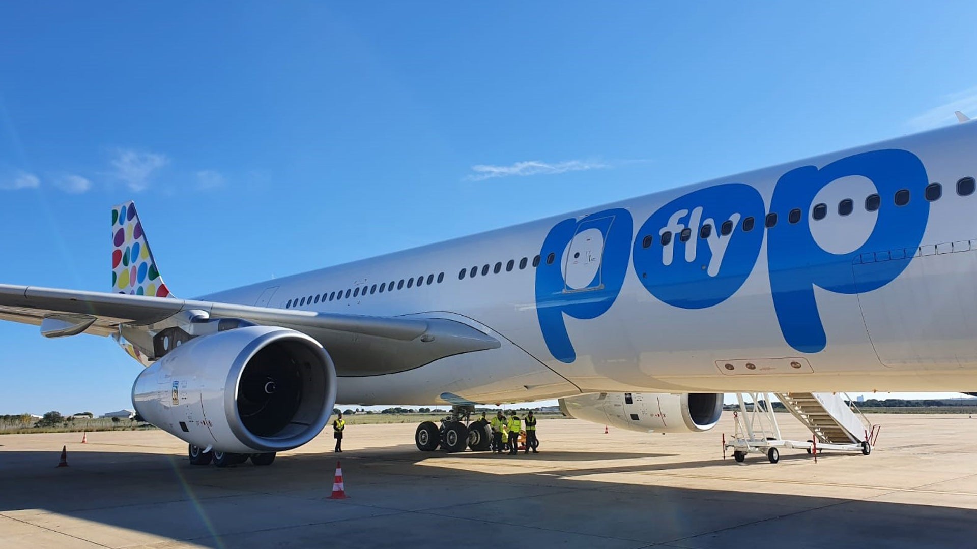 Colorful logo on side of flypop aircraft, view from 45-degree angle close to plane.