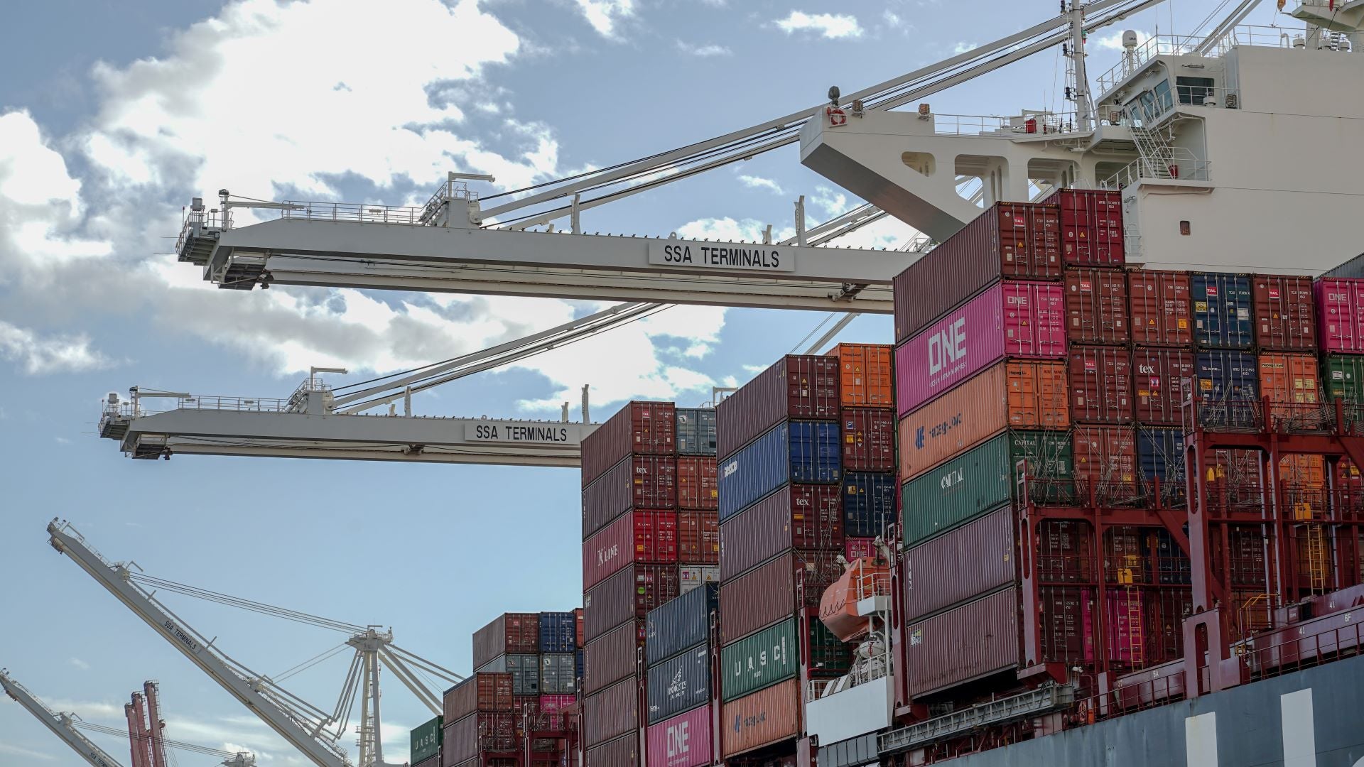 Port cranes extend sideways across a vessel full of containers.