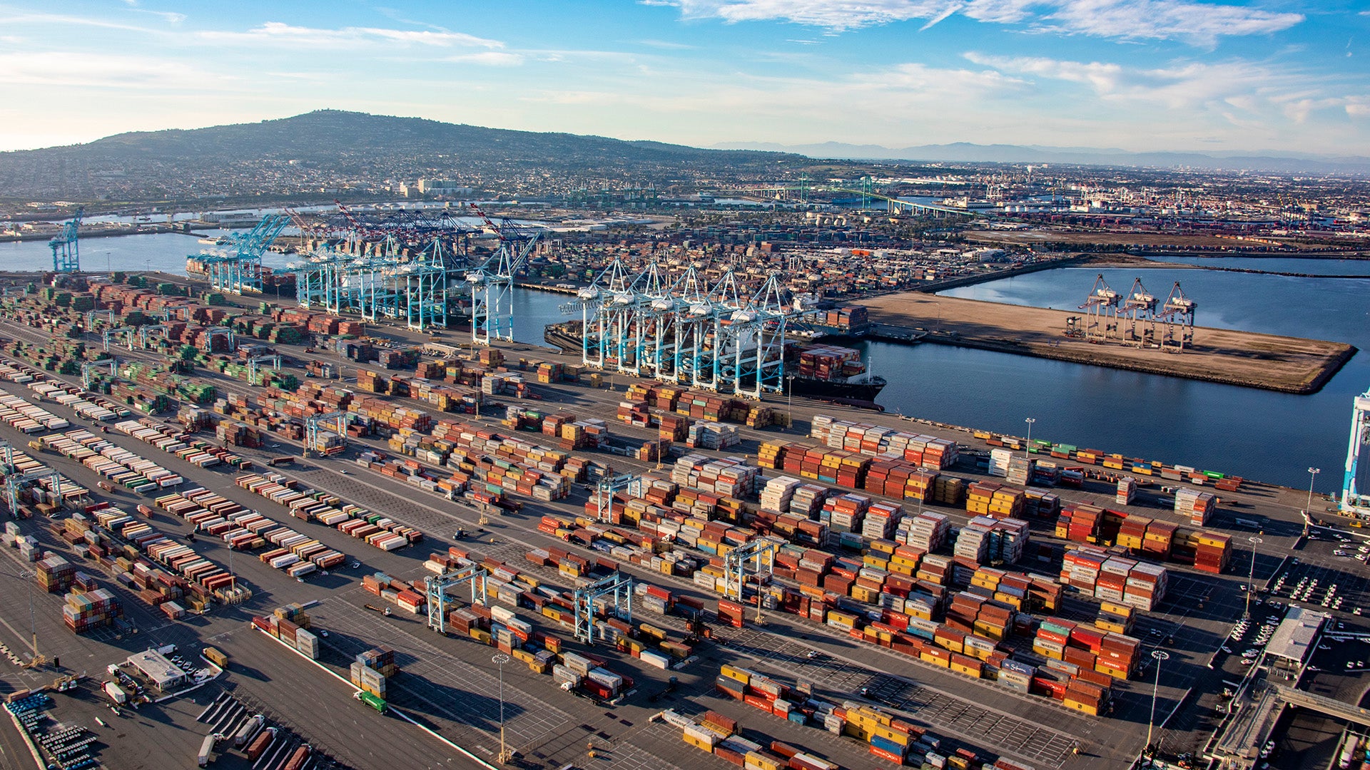 Aerial view of a large container terminal at a port, with cranes and containers.