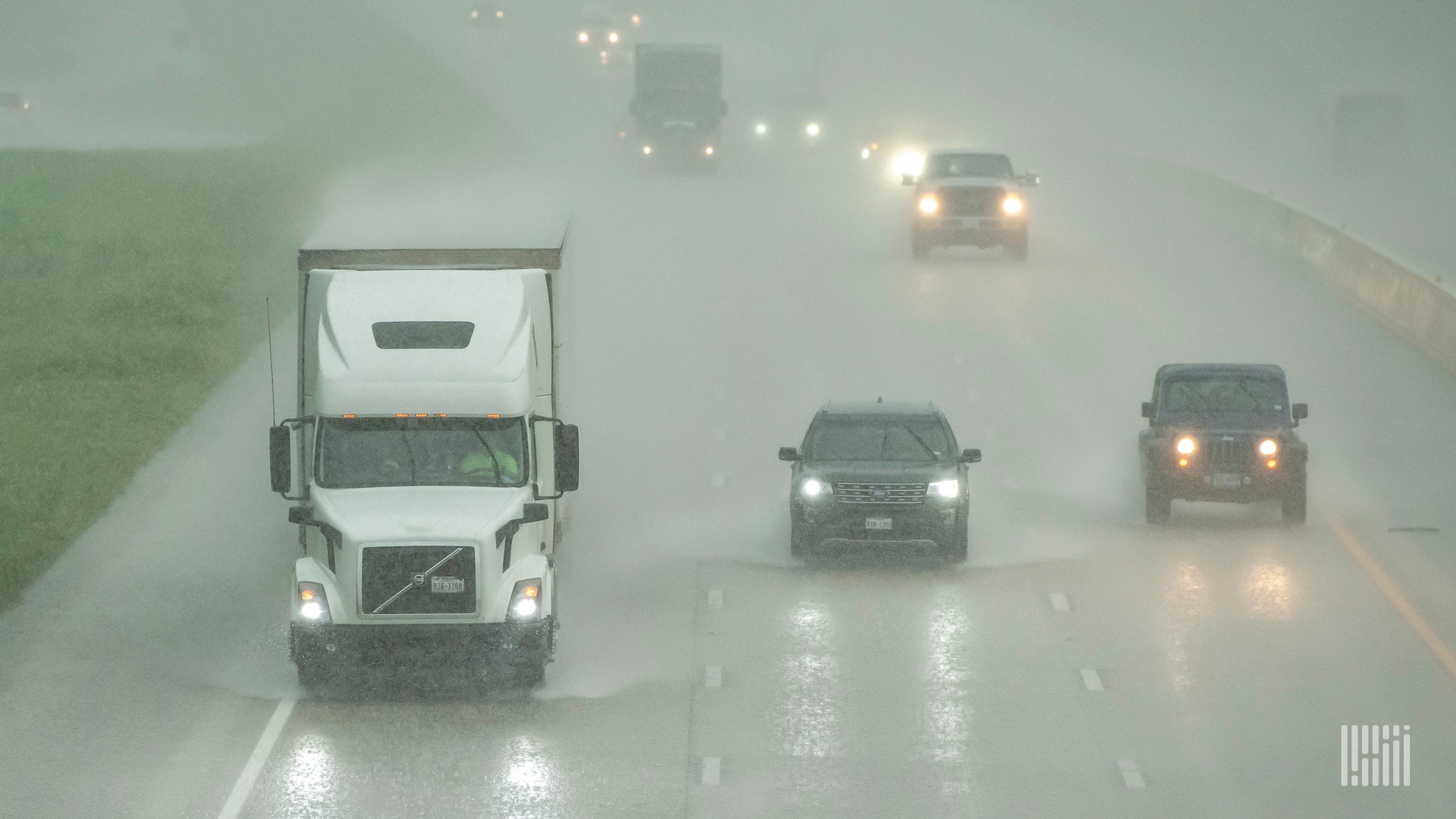 Cars and tractor-trailers in heavy rain.