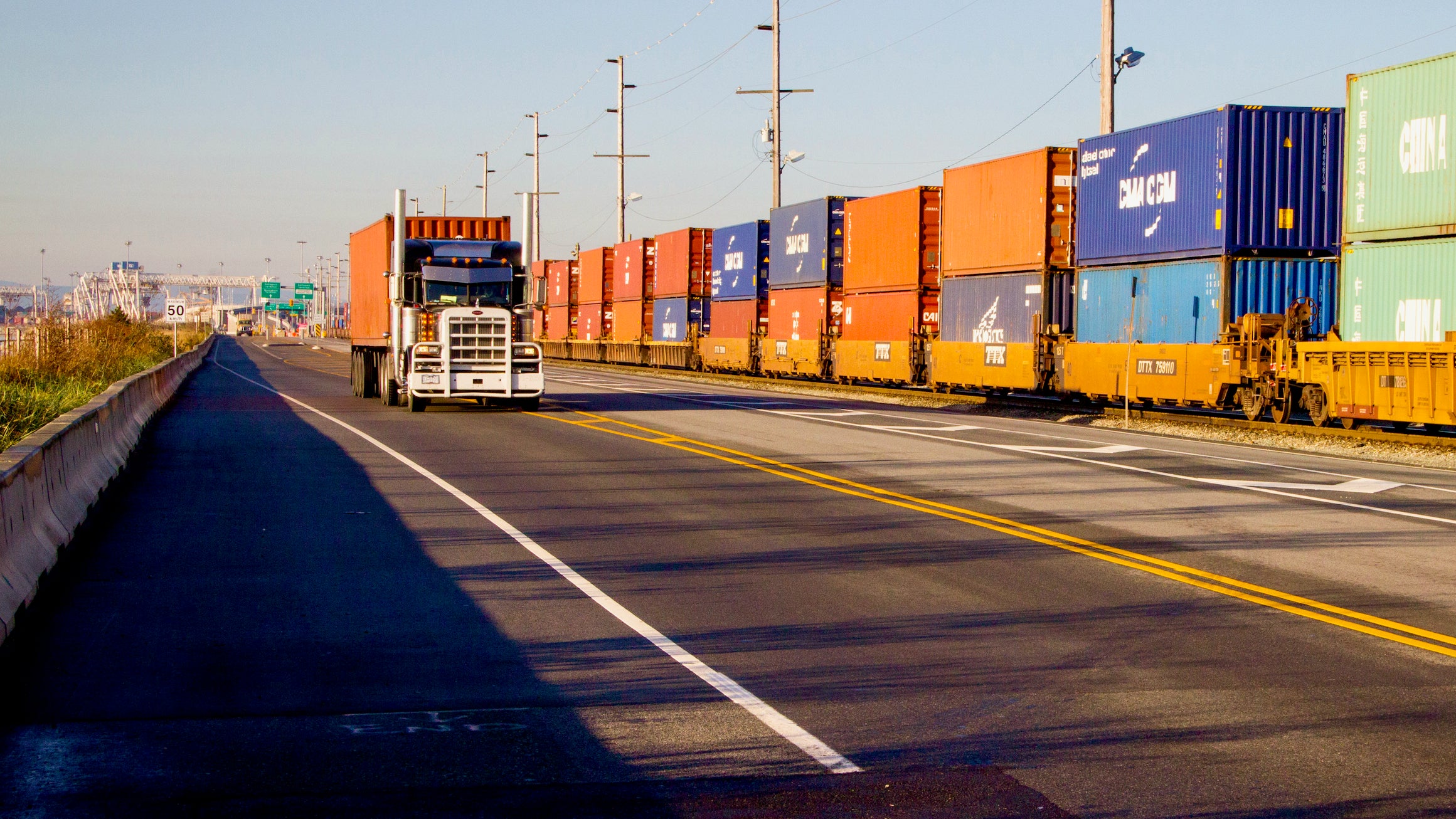 A truck a the Port of Vancouver passes a train with containers.