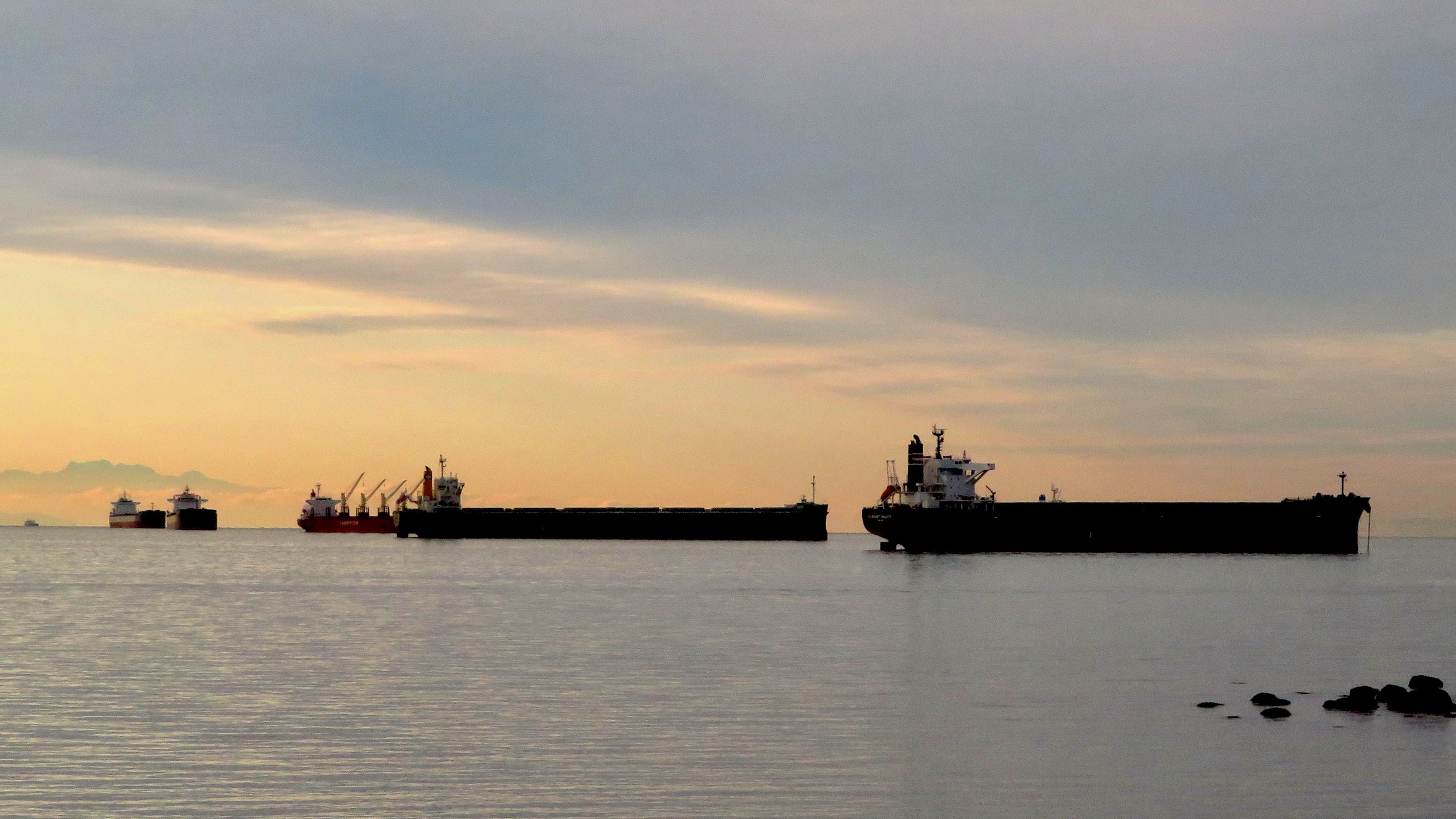 Three ships at anchor near the Port of Vancouver with the sun setting.