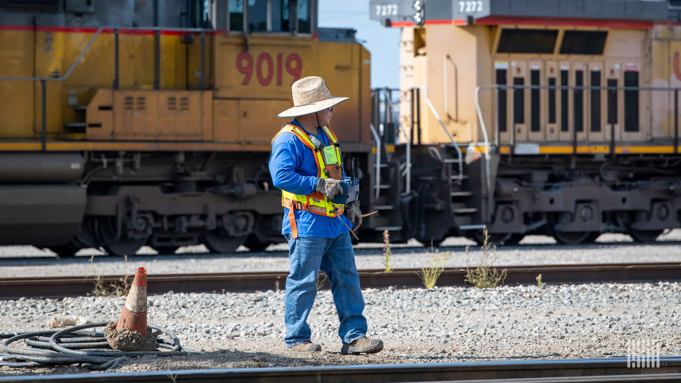 A photograph of a man expecting rail track at a rail yard.