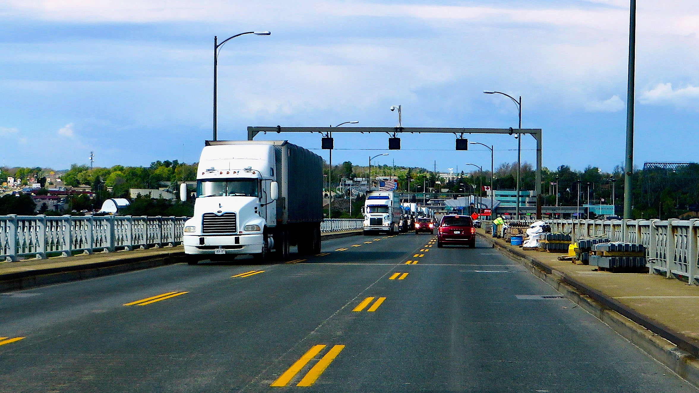 Trucks driving along a bridge at the US Canada border.