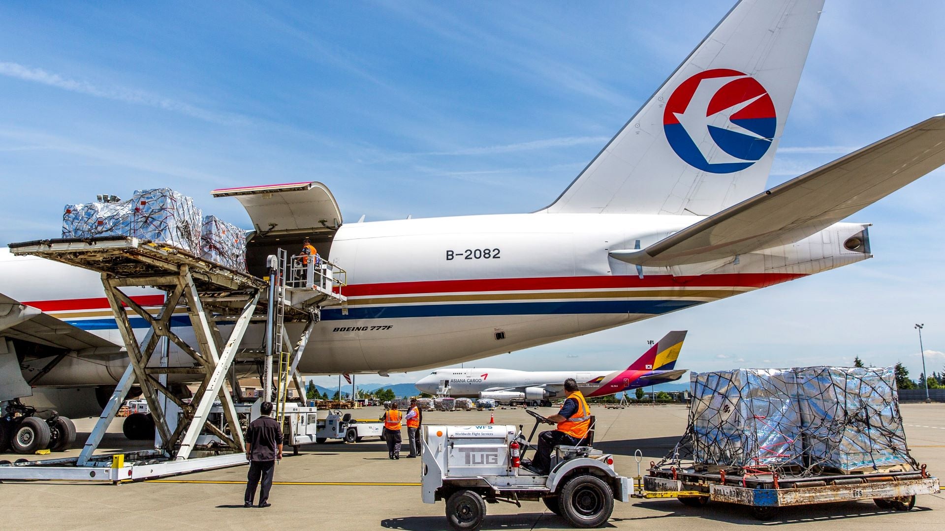 Sideview of back half of a big jet being loaded with cargo on a sunny day.