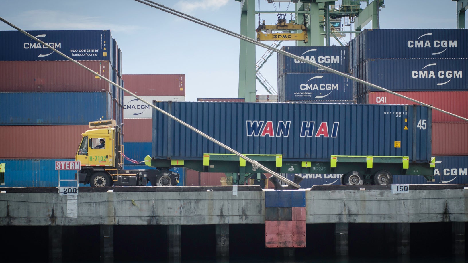 Mullticolored containers on dock with a shuttle truck.