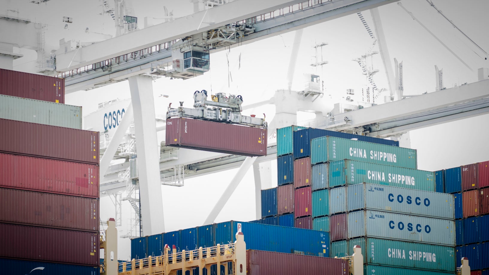 A crane lifting containers from a vessel at a port.