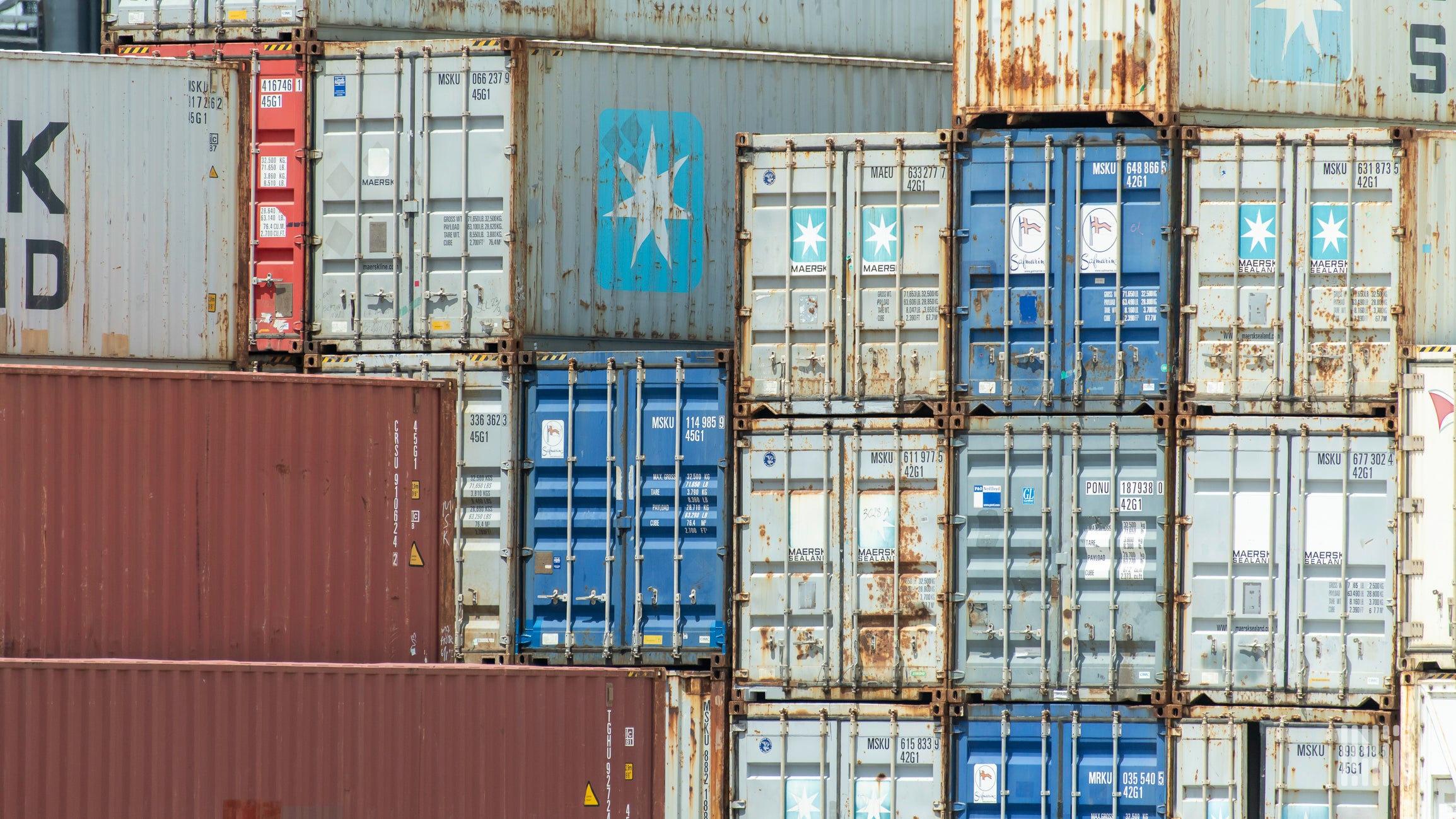 A close-up photograph of stacks of intermodal containers.