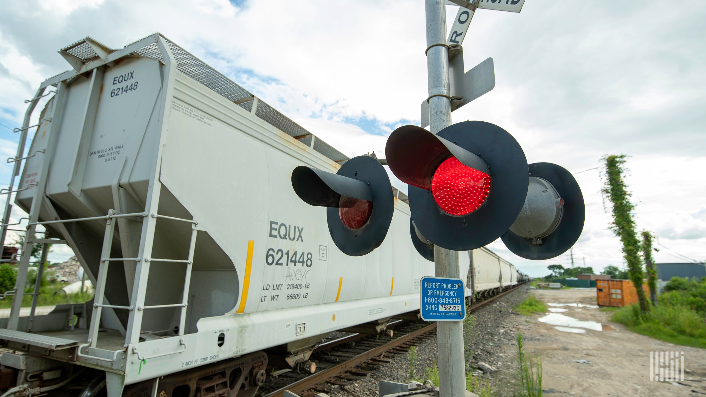 A photograph of a train crossing a rail crossing.