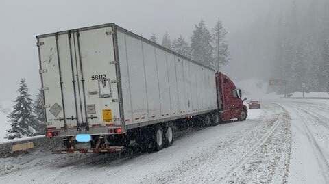 Tractor-trailer on side of snowy Washington state highway.